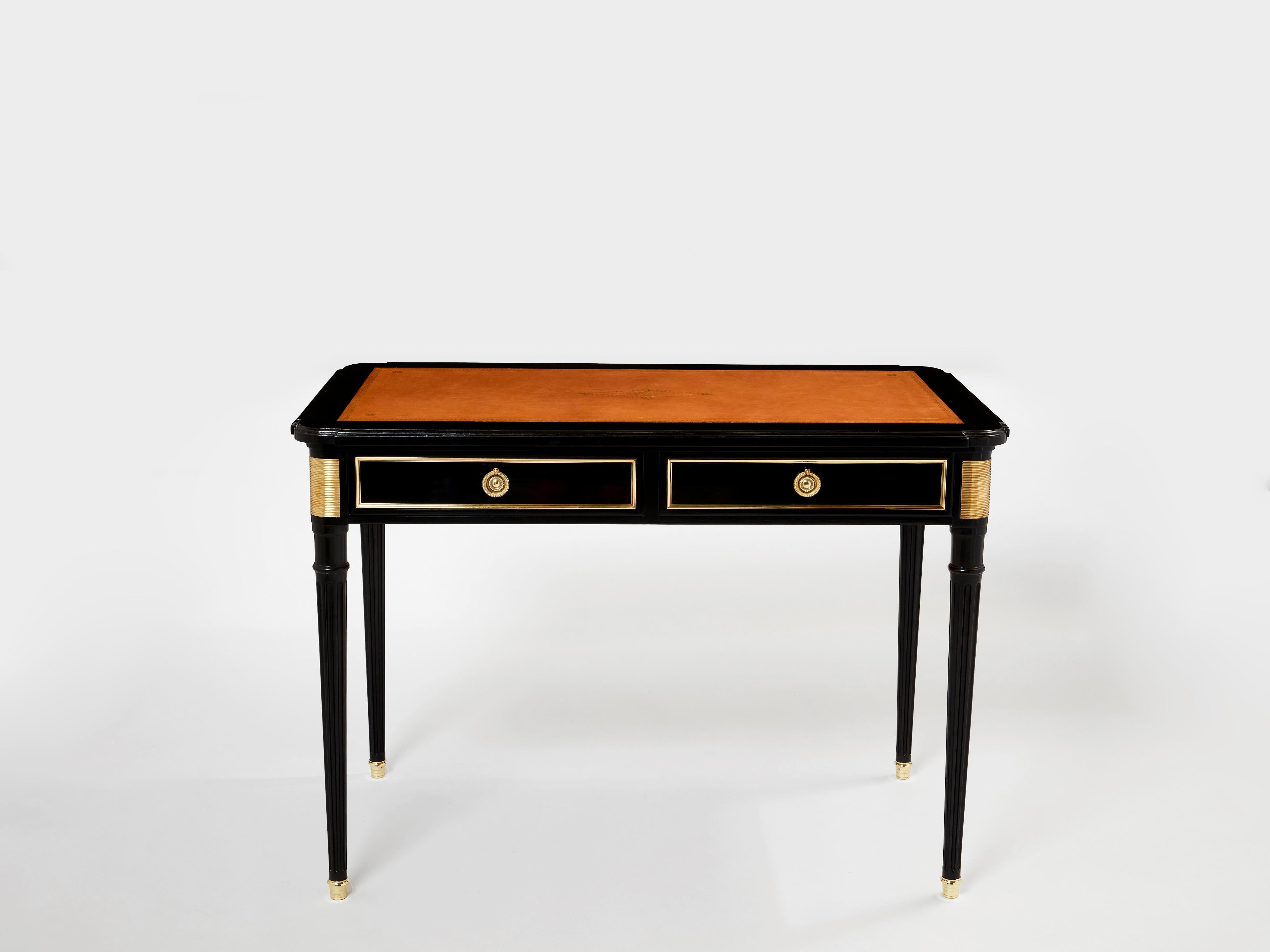 This beautiful Louis XVI style ebonized desk stamped Maurice Hirsch has been made in the early 1960s with black varnished mahogany wood, cognac leather top, and brass decor and accents. With its sleek rectangular bureau plat shape, fluted feet with