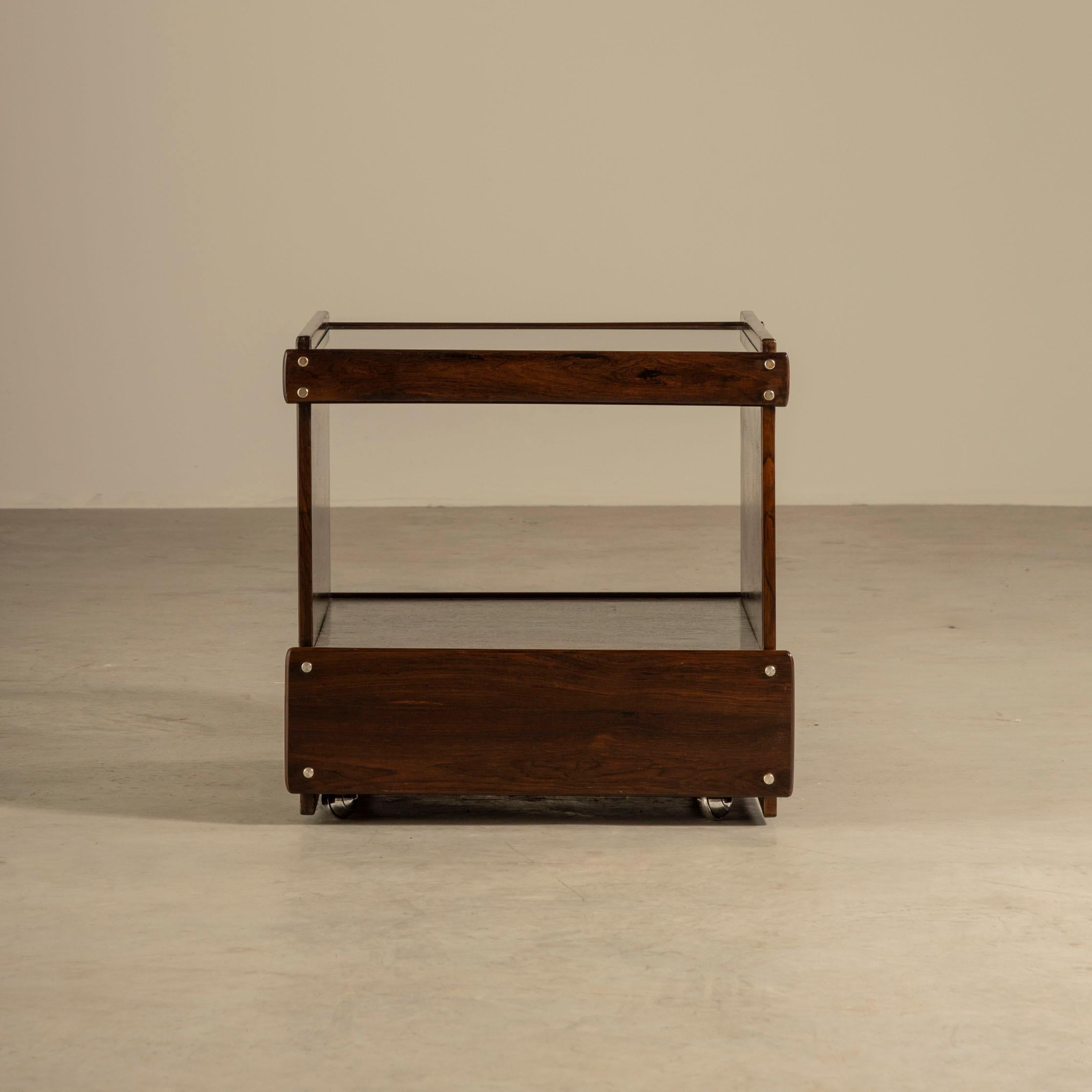 This Brazilian hardwood cart/trolley designed by the renowned architect and designer Sérgio Rodrigues in the 1960s is truly exceptional. The clean and modern look of the glass top is beautifully juxtaposed with the minimalist design and the natural