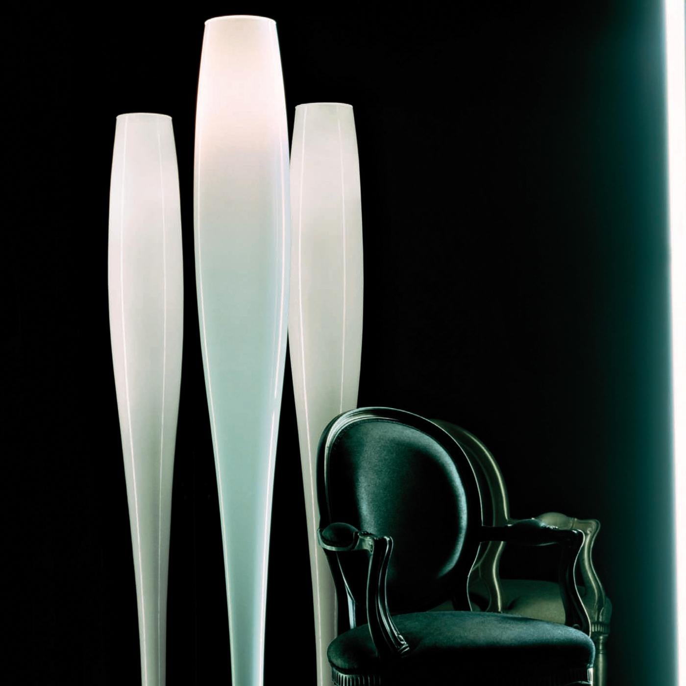 This floor lamp's simple geometry and organic shape deliver a striking allure and will enliven a modern interior with its soft light. Featuring an elongated shape that enlarges towards the top, the milky white diffuser of hand-blown Murano glass