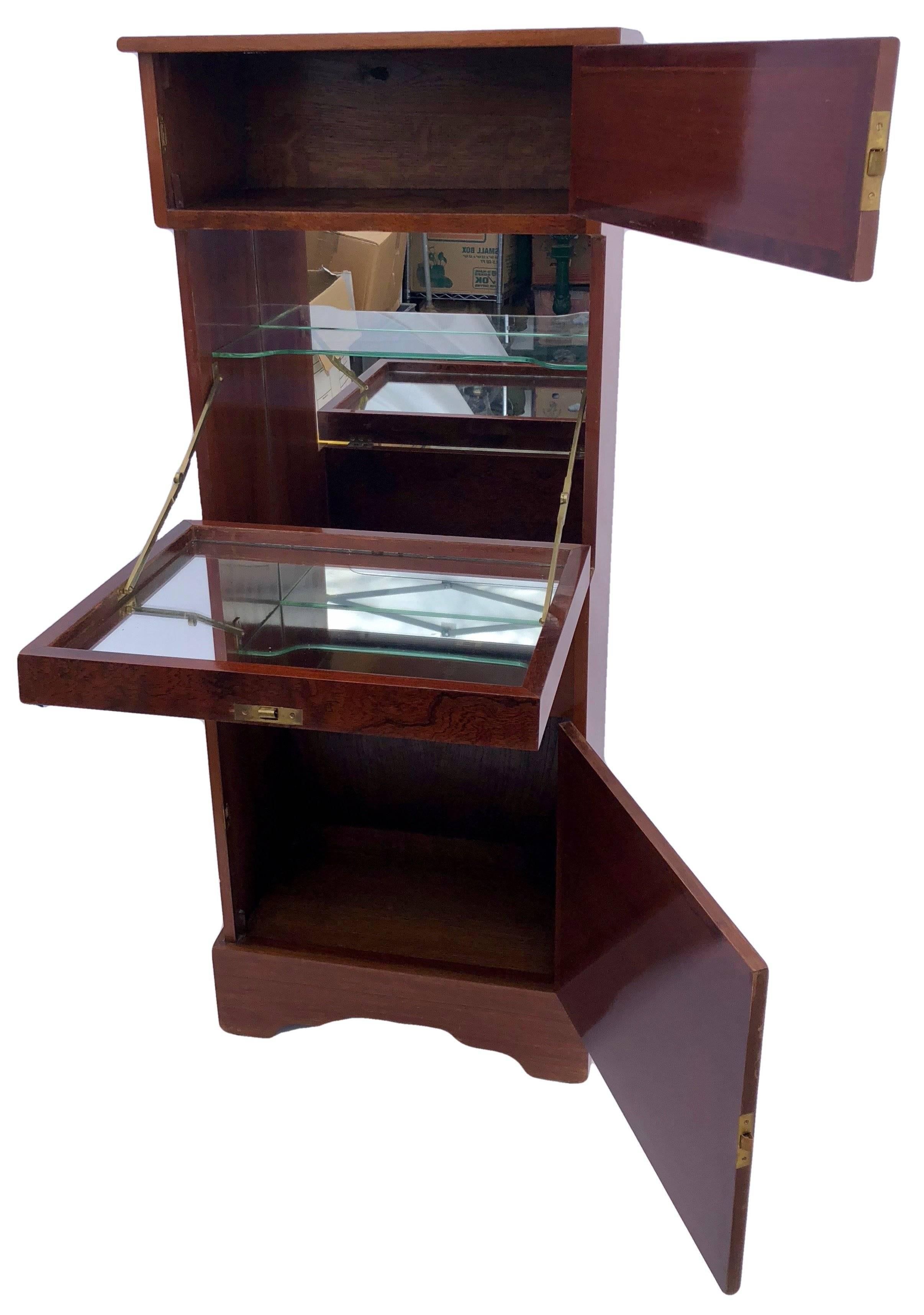 This 1950s standalone ship dry bar has an abattant has both an interior mirror and drop down mirror that is used as a small preparation table. It also has a glass shelf normally used for bar accessories. These mirrors make all the glassware glow and