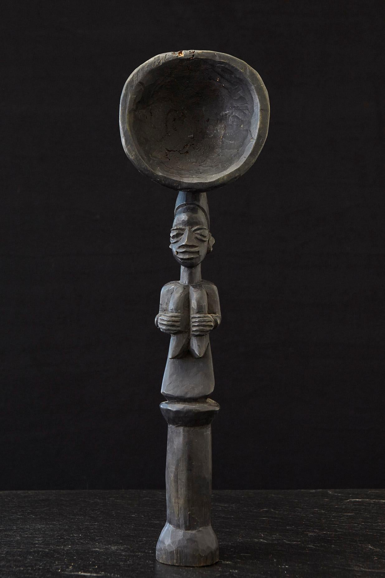 Large carved wooden spoon in the shape of a standing female figure, with a round bowl over her head, Yoruba People, circa 1960s.

The numbers are the inventory numbers from Penn State University and Lehigh University.  
Exhibited: The Pennsylvania