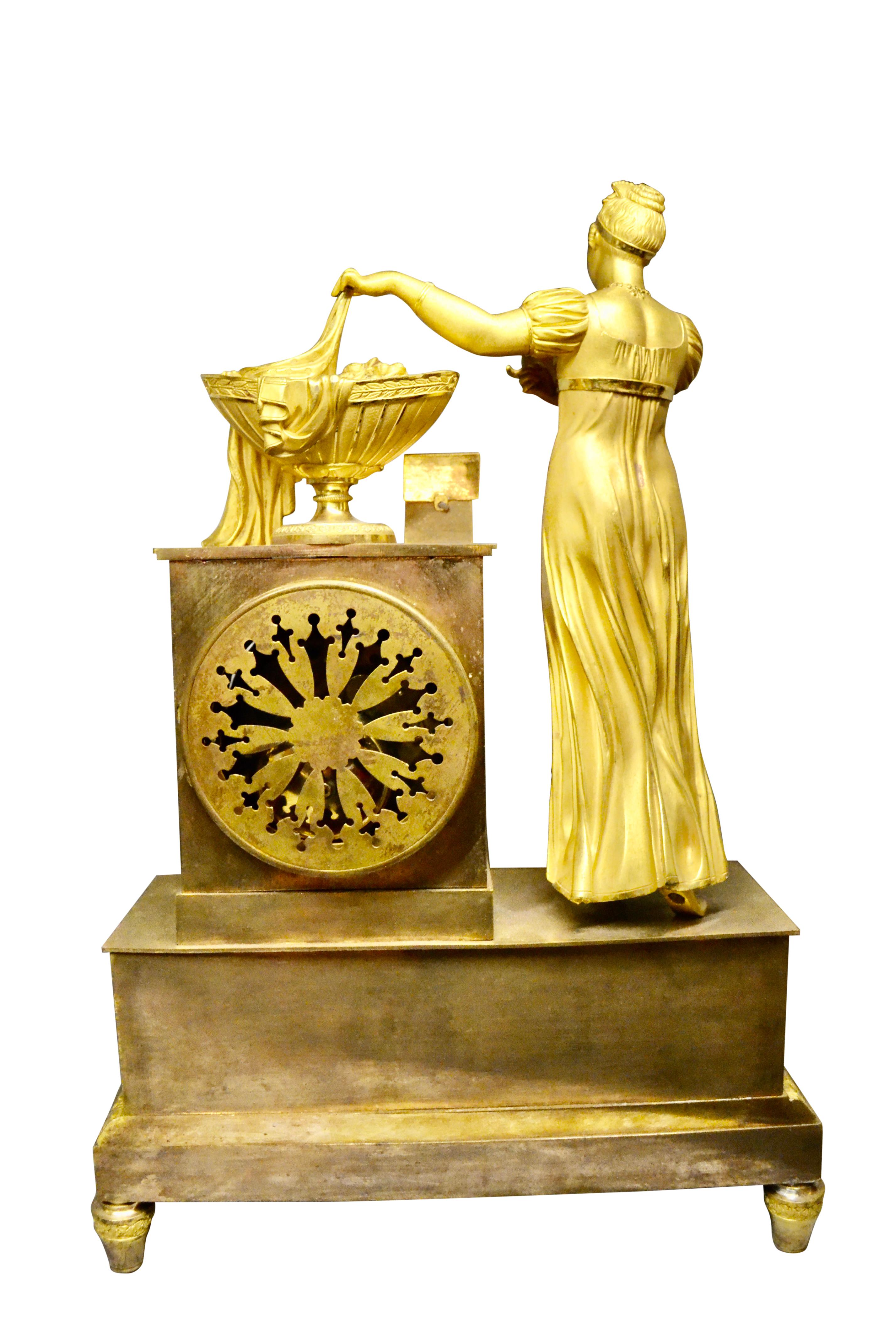 Early 19th Century Empire Gilt Bronze  Clock of Standing Classical Lady Unveiling an Urn of Plenty For Sale