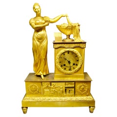 Bronze doré Empire  Pendule représentant une dame classique debout dévoilant une urne d'abondance