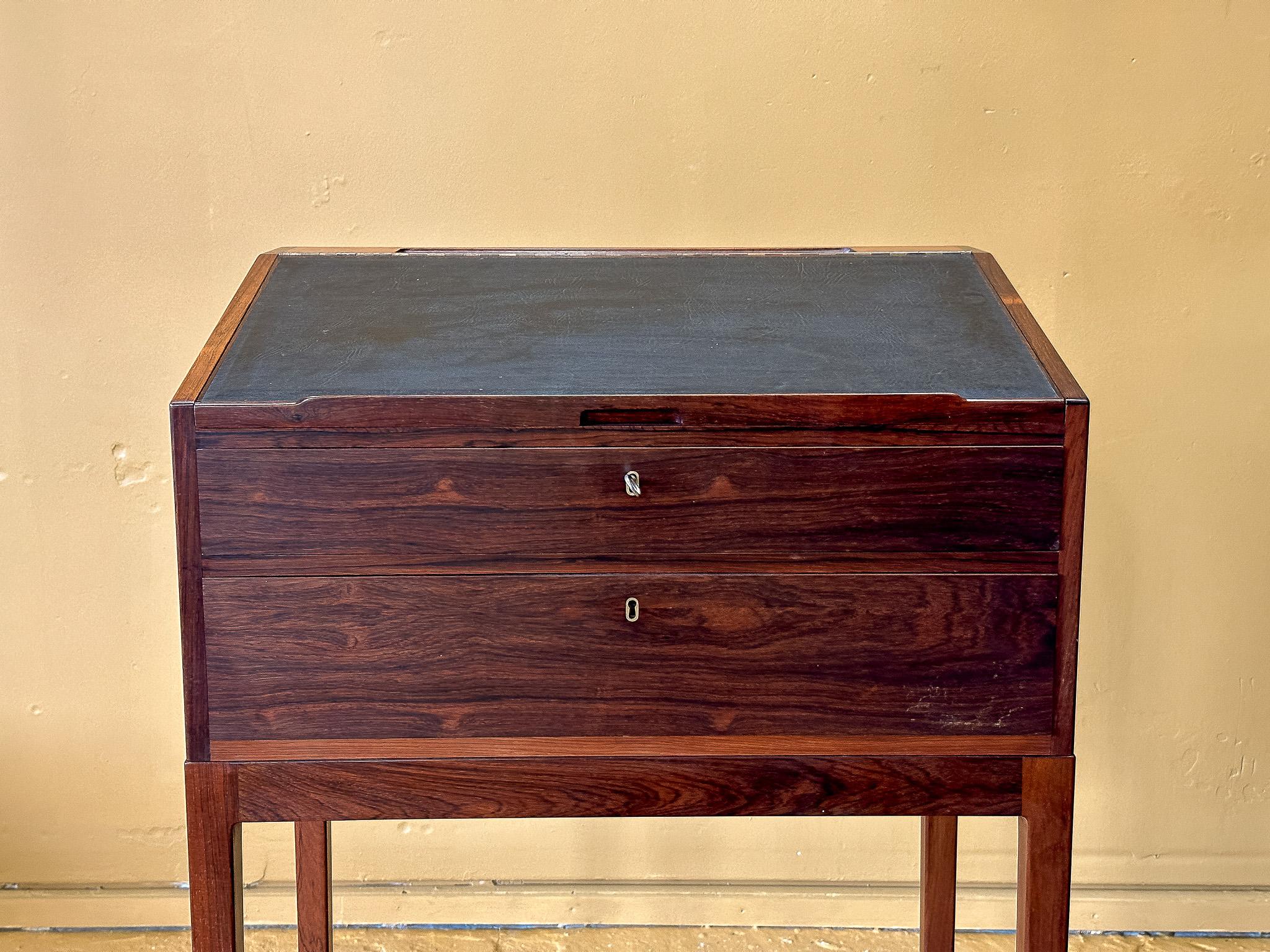 This Danish mid-century standing desk is a striking example of Scandinavian craftsmanship, combining functionality with a refined aesthetic. Made from richly grained hardwood, the piece showcases deep, warm tones with a lustrous finish that