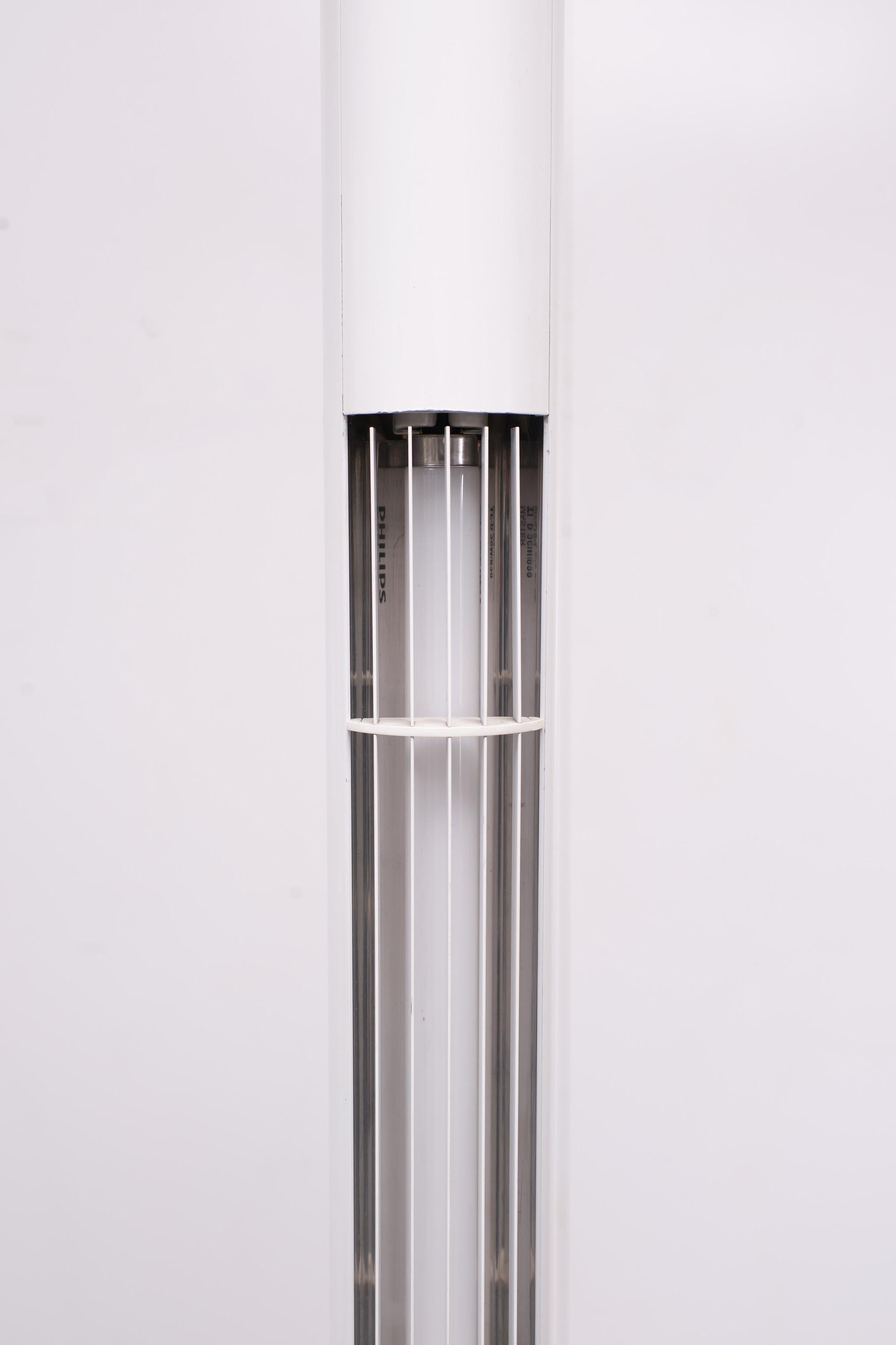 A typical design lamp from the 1980s. This lamp is a standing TL Tube in a white frame with a White front raster. its in a good vintage condition with only some signs of use on the foot of the lamp. Metal pole stand and floor plate.