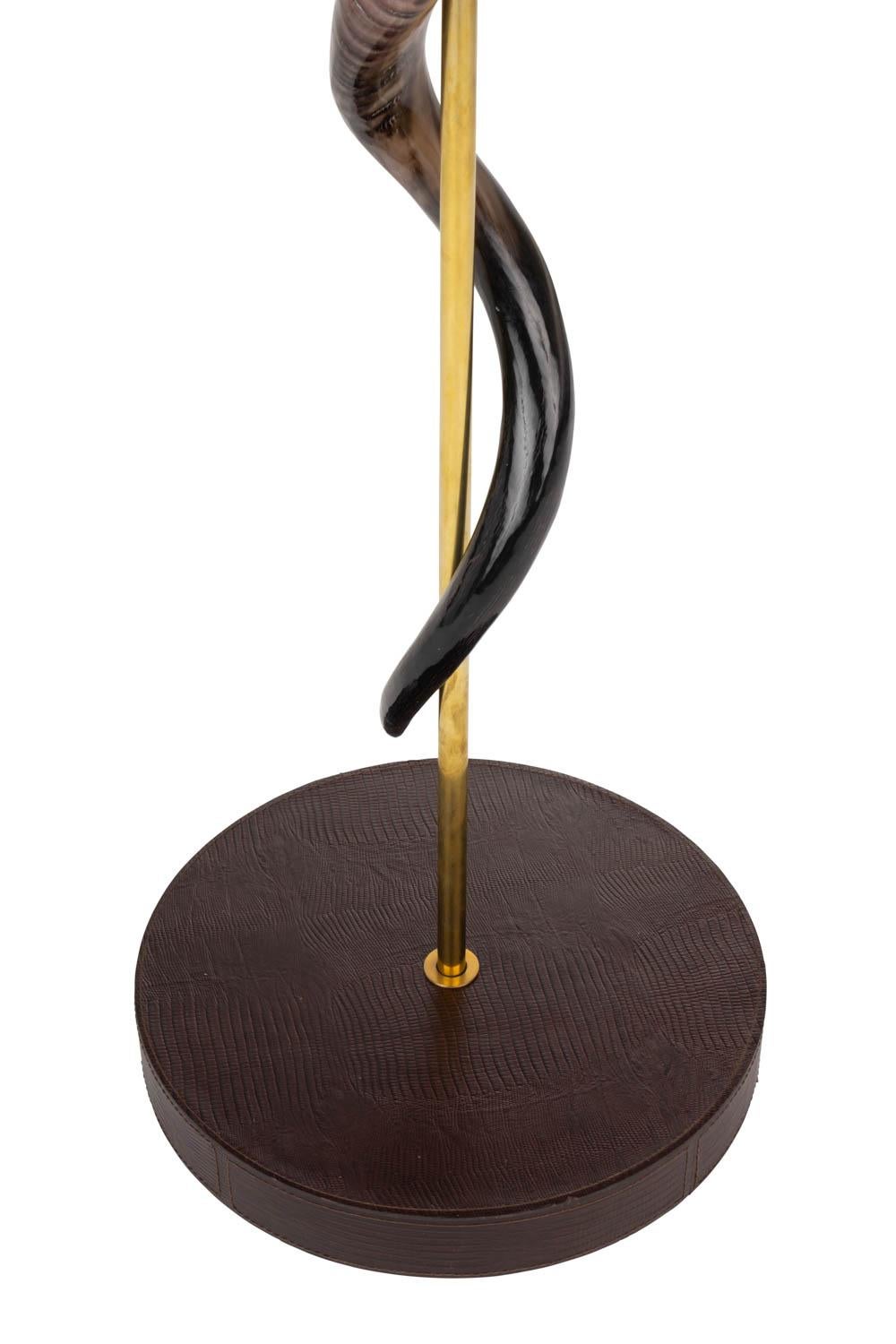 Handcrafted in South Africa, this naturally elegant floor lamp features two inverse African kudu horns encirling a brass rod above a round wooden base, which is wrapped in top-stitched embossed leather. All hide and horn has been sustainably sourced