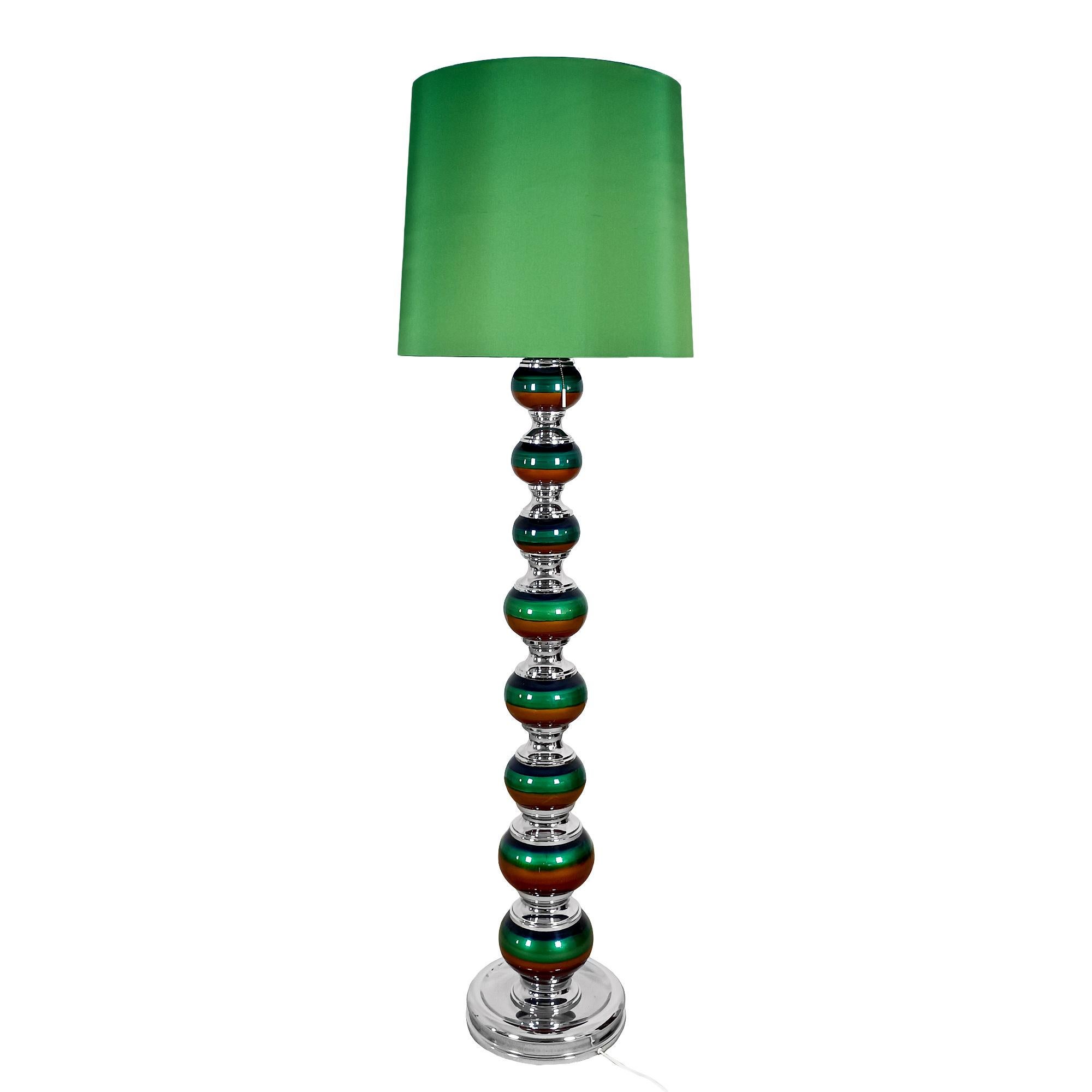 Lampe sur pied avec corps en boules de céramique dans des teintes de  bleu-vert et ocre, maintenus par des pièces métalliques chromées, comme le socle. Abat-jour renouvelé en tissu vert.

Espagne vers 1970