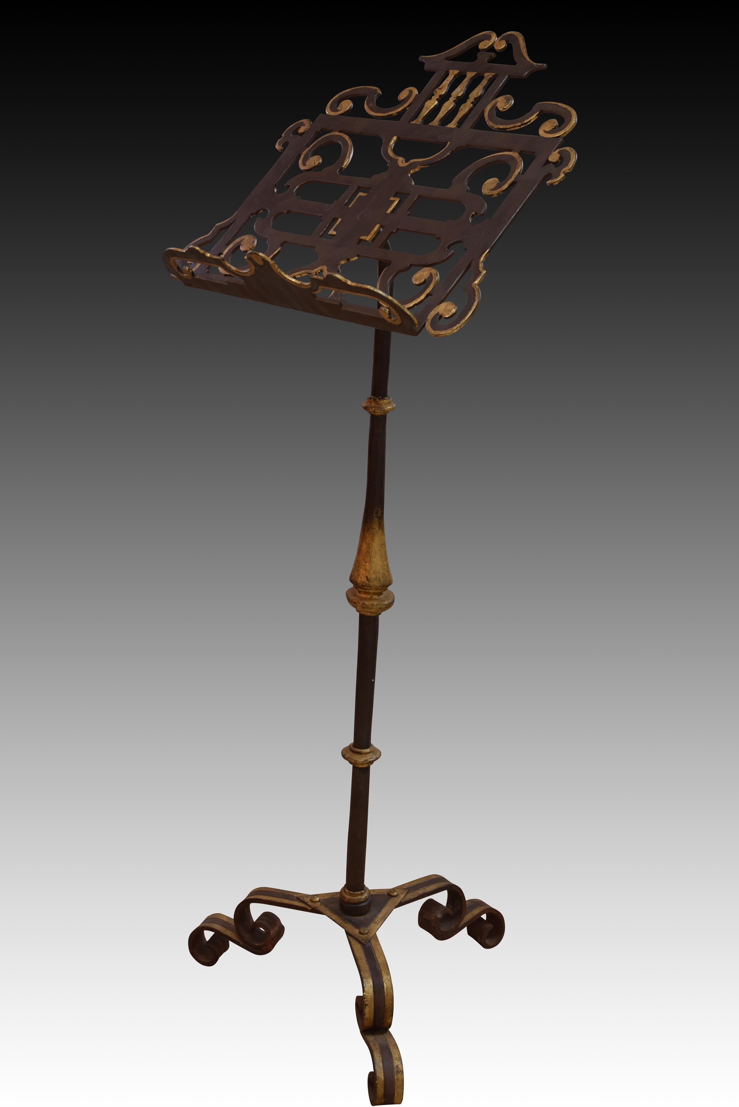 Standing lectern in wrought iron. Twentieth century. 
On three legs with volutes stands a foot decorated with balustraded shapes and a flame towards the center, which supports and raises the lectern, which stands out for its simplified architectural