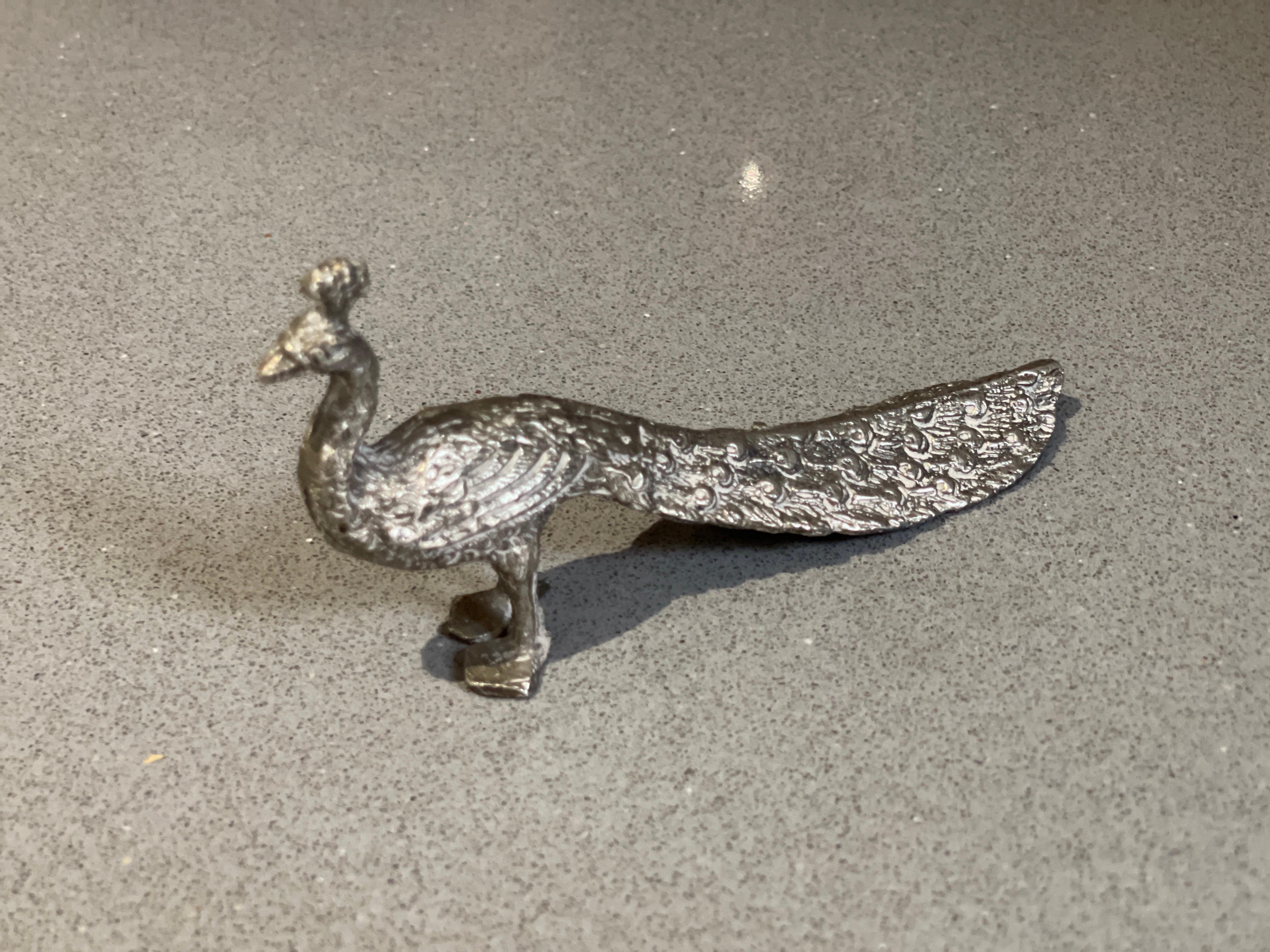 Majestic and regal, this standing silver-plated peacock exudes elegance and grace.
The impressionistic treatment of surface texture refers to the clay from which it was crafted.   size:3x12x5 cm
SILV71