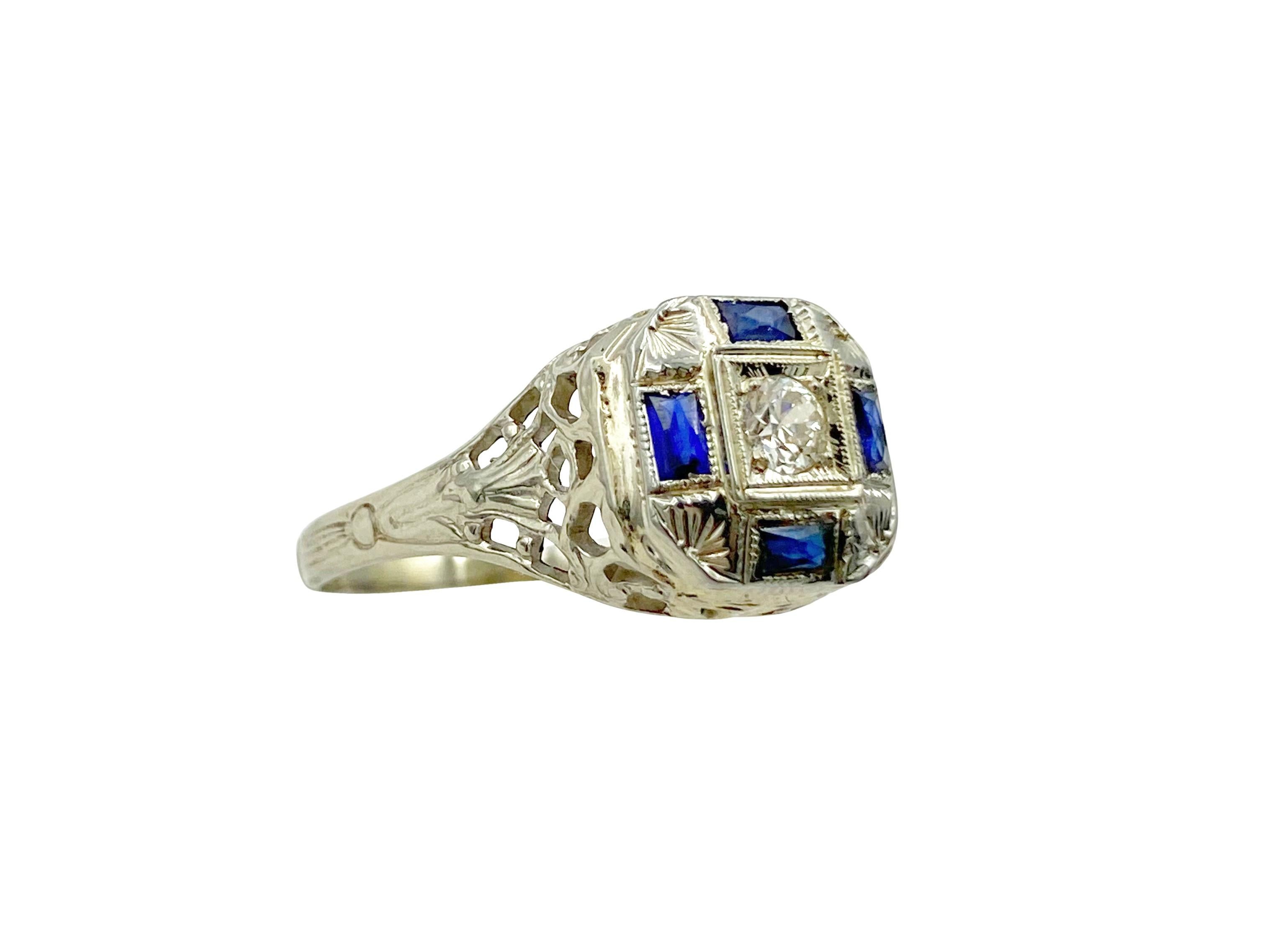Unique antique diamond and sapphire ring with an octagonal-shaped domed ring front. Four rectangular French cut blue sapphires surround a sparkling old European cut center white diamond. The 14k white gold setting is accented with hand-engraved palm