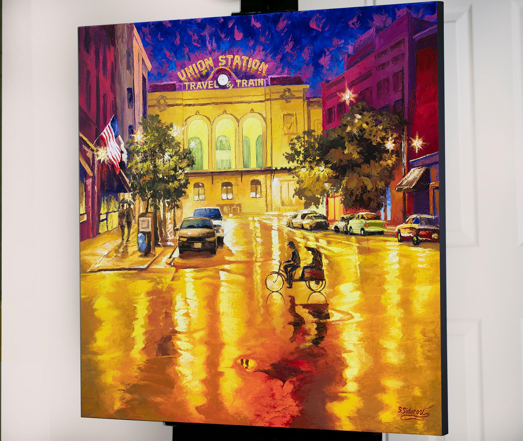 <p>Kommentare des Künstlers<br>Von der Union Station aus betrachtet, schafft der Regen eine romantische und gemütliche Atmosphäre in Downtown Denver. Autos parken auf beiden Seiten der Straße, während in der Mitte eine Fahrrad-Rikscha kreuzt. Ein