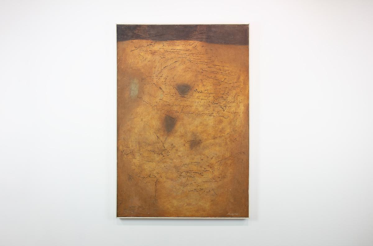 This Modern Abstract Expressionist painting by Stanley Bate is made with oil paint on board and features a warm, yellow and umber palette. The artist layers paint on the canvas, creating texture among softly blended colors in a highly abstract