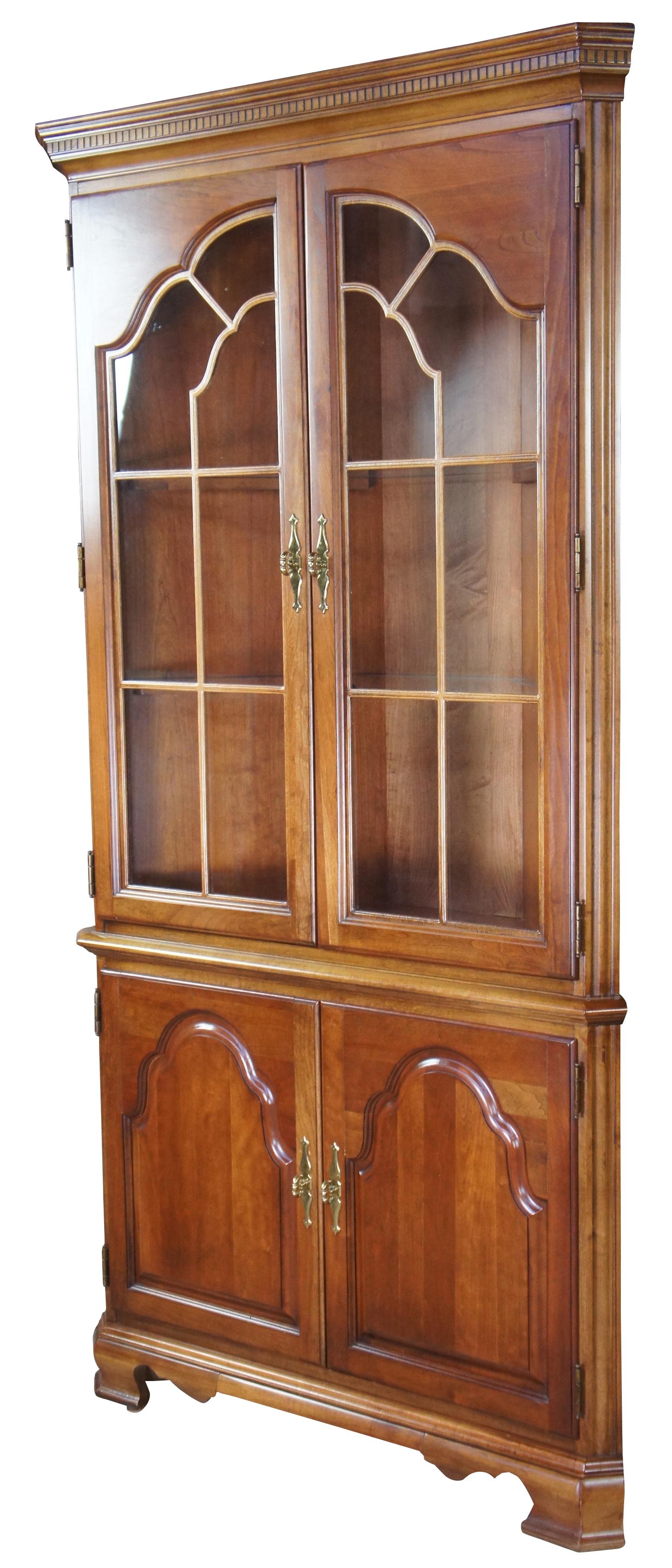 Stanley furniture Chippendale or Queen Anne style corner cabinet. Made of cherry with paneled glass doors, interior glass shelves illuminated from above, and lower cabinet.
 