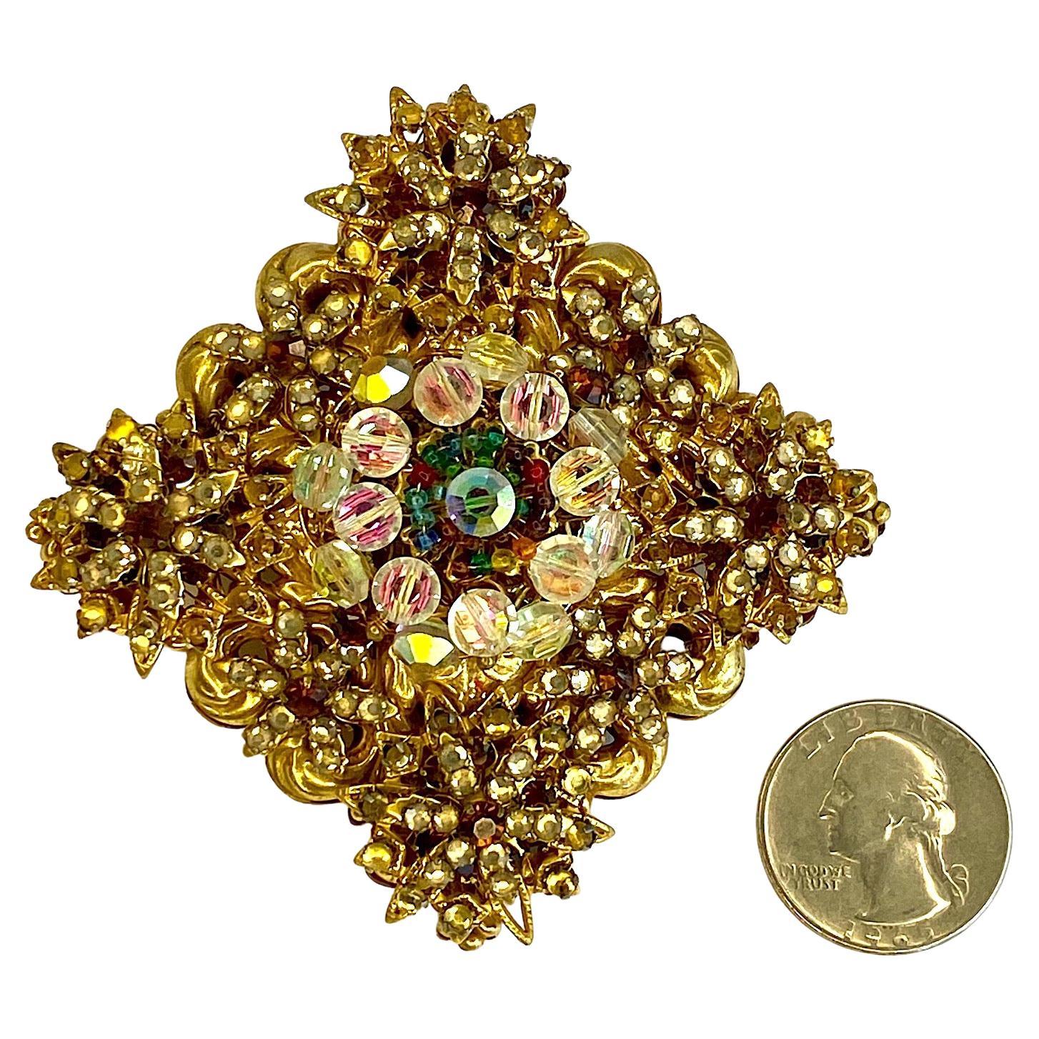 Presented is a lovely brooch by Stanley Hagler from the 1980s. Hand made of carefully threaded individually set clear flat back rhinestones, aurora borealis rhinestones, purple rhinestones, iridescent crystal beads and small red and green seed