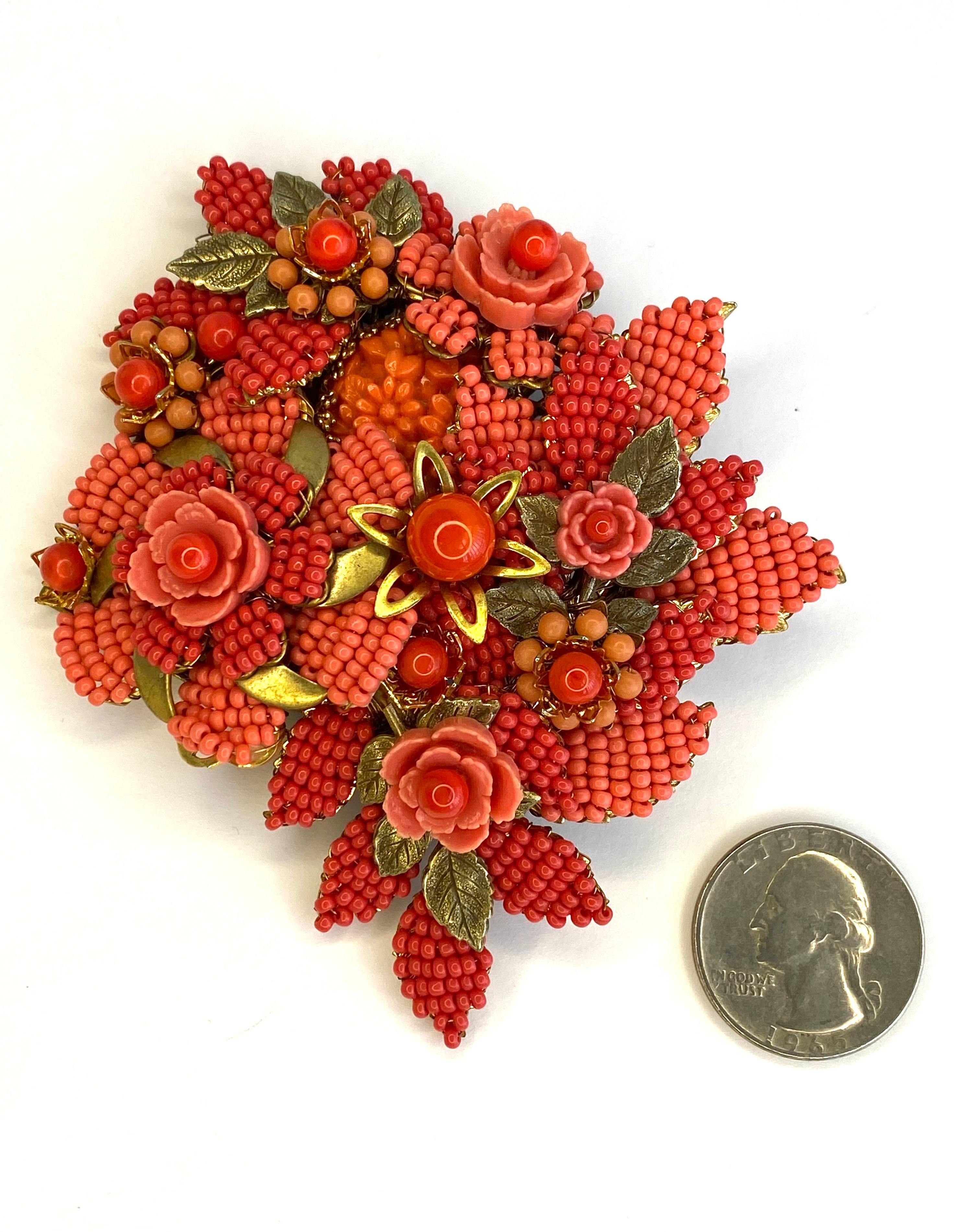 Lovely and large floral brooch by Stanley Hagler from the 1980s. Hand made of threaded coral glass beads on brass wire with four matching color resin flowers. The beads and flowers are strung onto a gold branch of leaves mounted on an antique gold