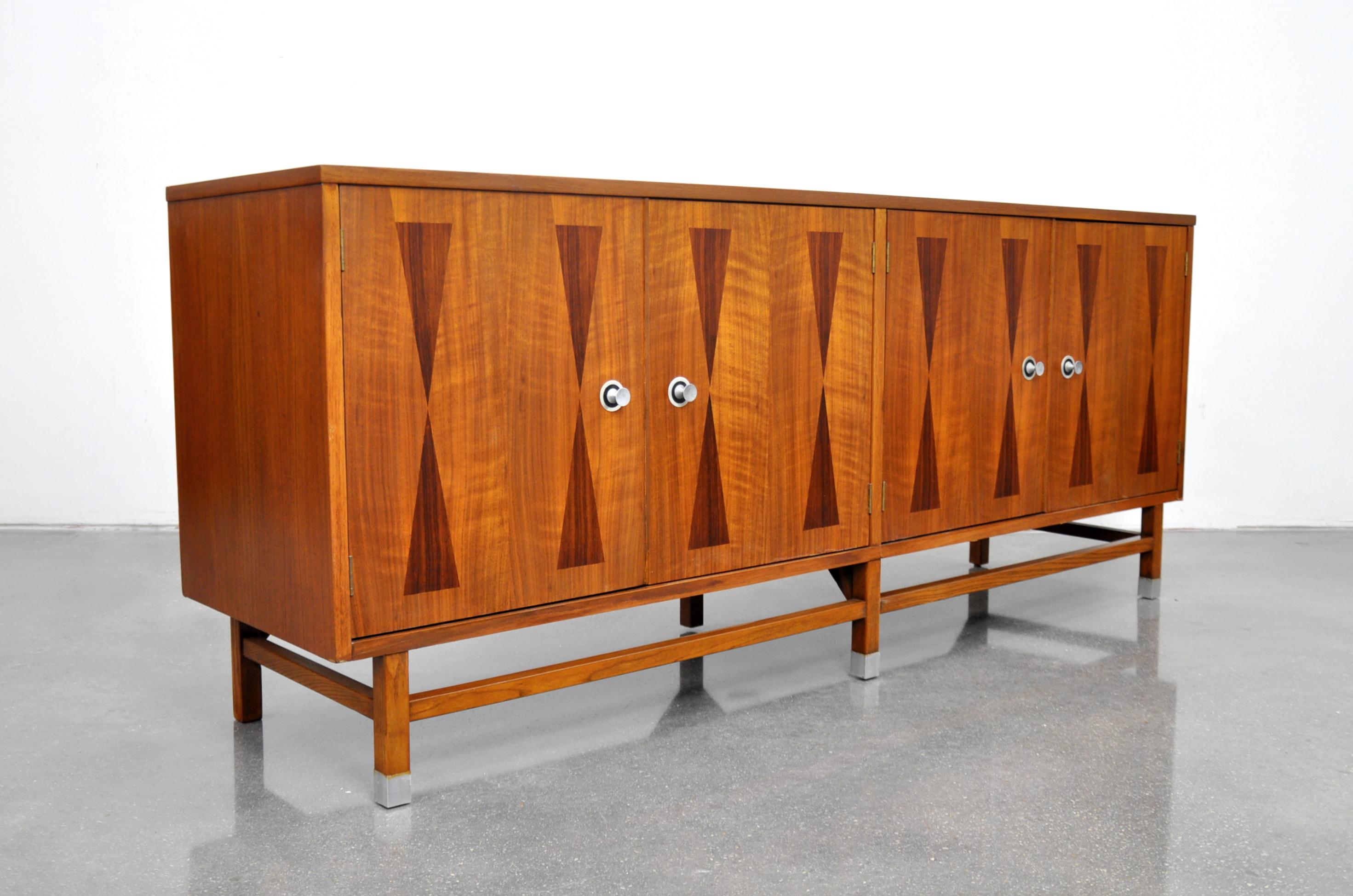 Gorgeous Mid-Century Modern bar cabinet from Stanley's Linear Precision Group dating from the mid-1960s. The sideboard features a top with rosewood banding and four doors with hourglass rosewood marquetry inlaid fronts, opening to an interior fitted