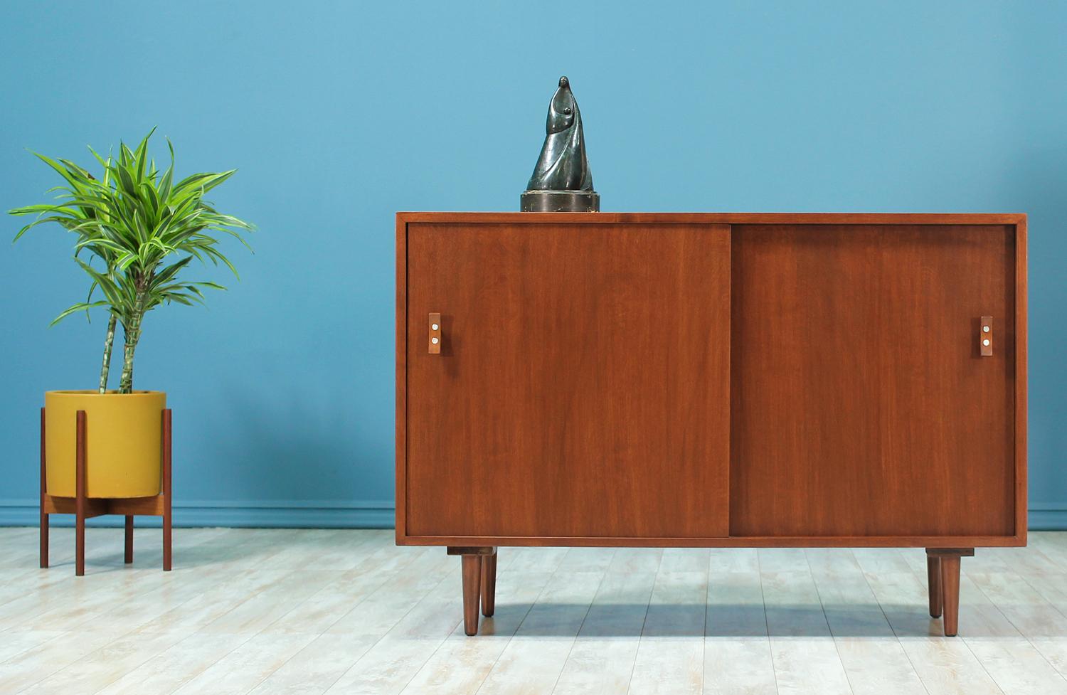 Mid Century Modern credenza designed by Stanley Young for Glenn of California and manufactured in the United States circa 1950’s. This stylish walnut credenza features a gorgeous grain detail showing throughout the casing and sits on tapered legs.