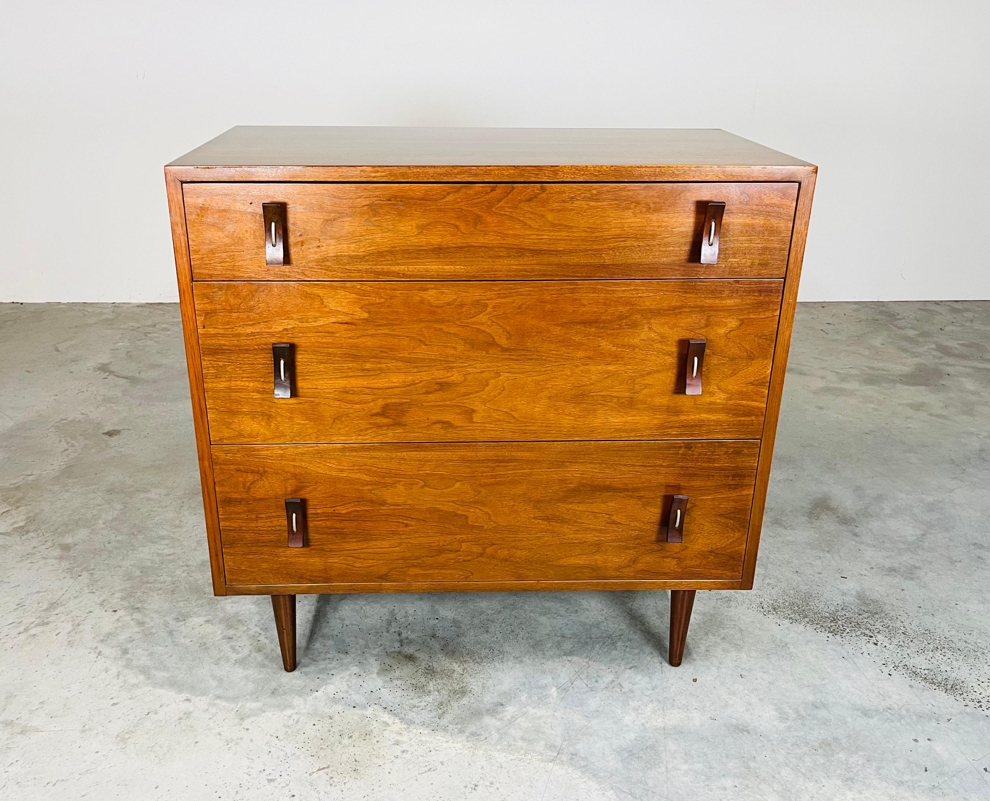 Un'eccezionale cassettiera a 3 cassetti in noce, disegnata da Stanley per Glenn Of California, con tiretti in noce curvati al contrario e fissati tramite un'asola in nichel che si avvita all'interno dei cassetti. Un design accattivante e realizzato