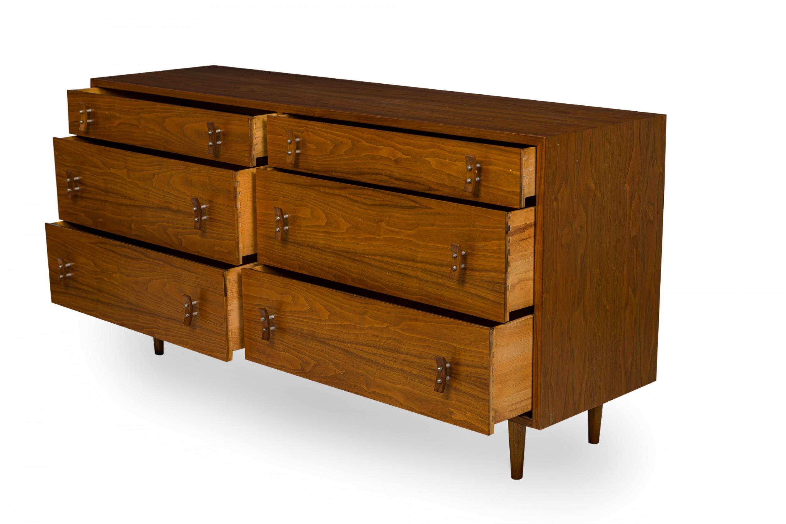 American Mid-Century rectangular walnut six-drawer low chest with two sections of three drawers each with curved wooden drawer pulls attached by two rivet points in a walnut case, resting on four tapered walnut legs. (STANLEY YOUNG FOR GLENN OF