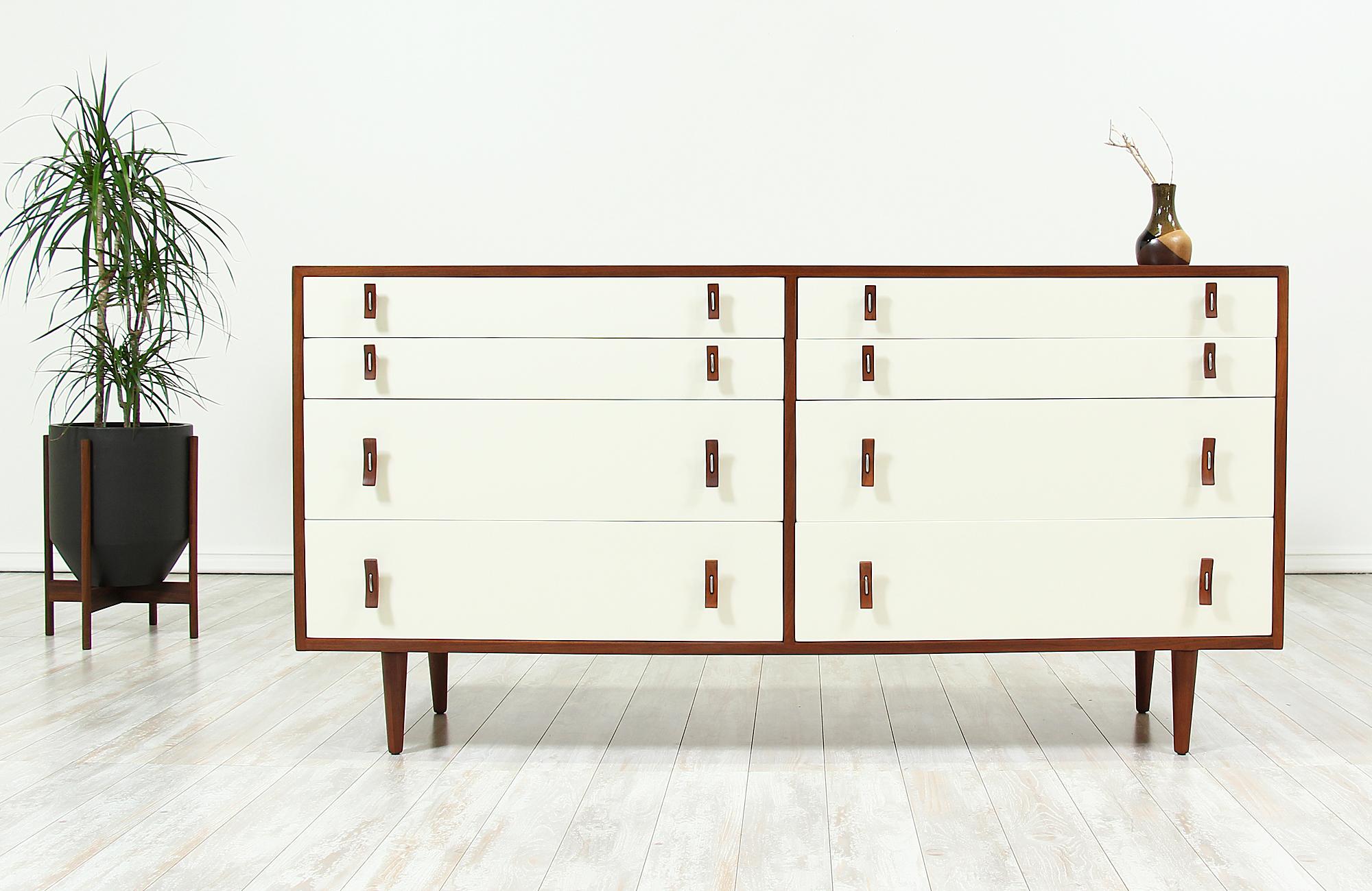 A beautiful eight-drawer dresser designed by Stanley Young for Glenn of California in the United States circa 1950s. This stylish dresser features the designer’s signature bentwood and steel pulls on each of the white lacquered drawers that open to