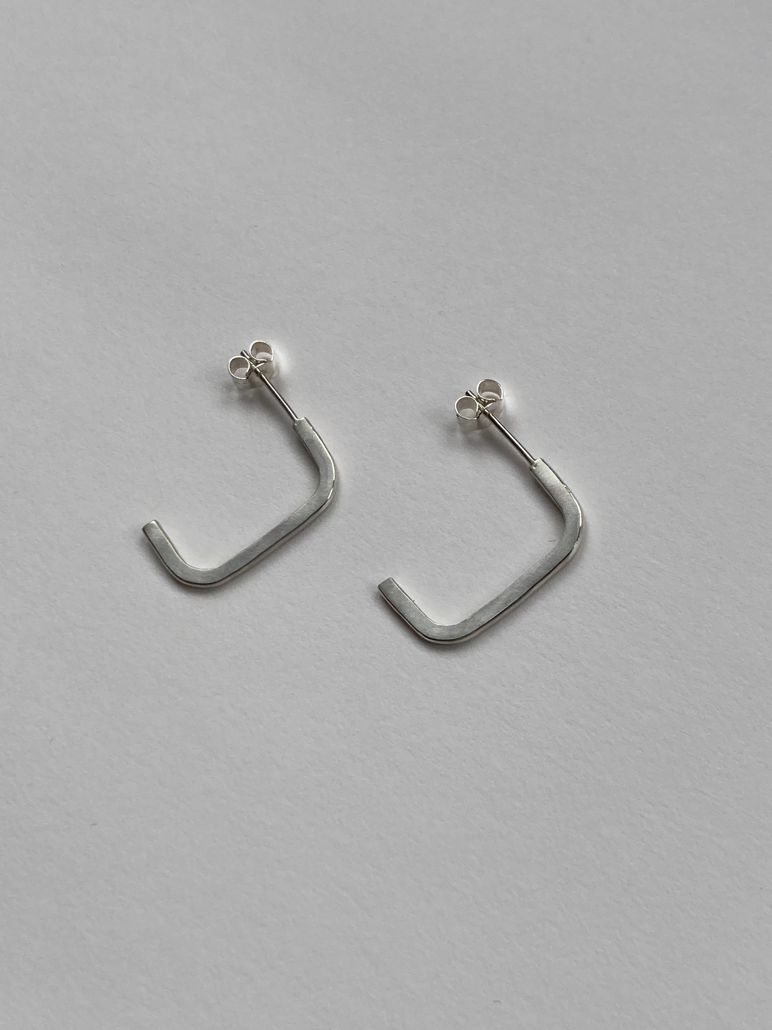 Elegant stud earrings made from forged wire, formed into a half folded square. 

The polished inside surface catches the light when worn. 

They are secured to the ear with a classic butterfly back, and are a comfortable weight for everyday wear.