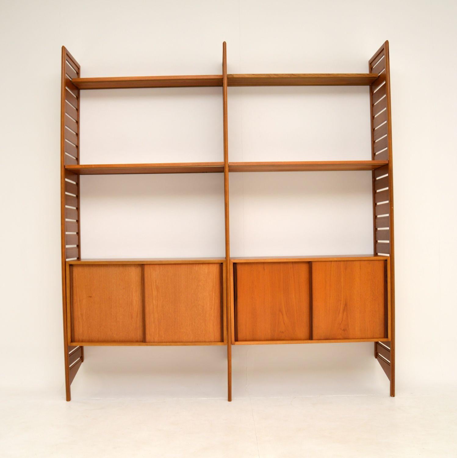 A stylish and very practical teak wall unit by Ladderax. This was made in England and dates from the 1960’s.

It consists of three side ladder rails, two sliding door cabinets, four shelves, and metal supporting rails for each unit. The shelves