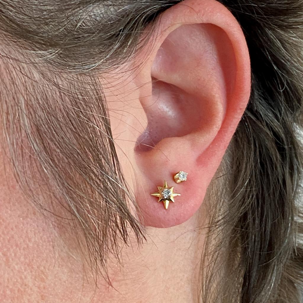 Accent your ear with these bright starburst diamond studs! At the center of each beautifully made star is a white gold setting holding a round brilliant diamond. These are solidly built everyday fine fashion earrings. Fine attention to detail makes