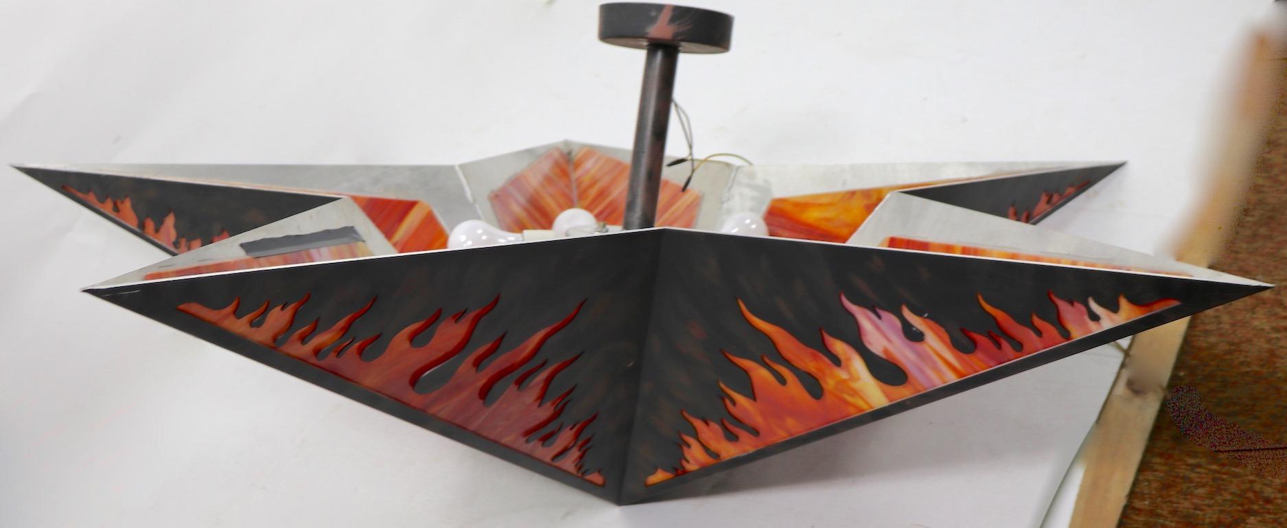L'ultime lustre décoratif de la Man Cave en métal peint et verre de scorie. Chaque élément triangulaire mesure environ 14 pouces de large au point le plus large x 21 L.
Ce luminaire dramatique accepte cinq ampoules standard à vis. Il est en bon