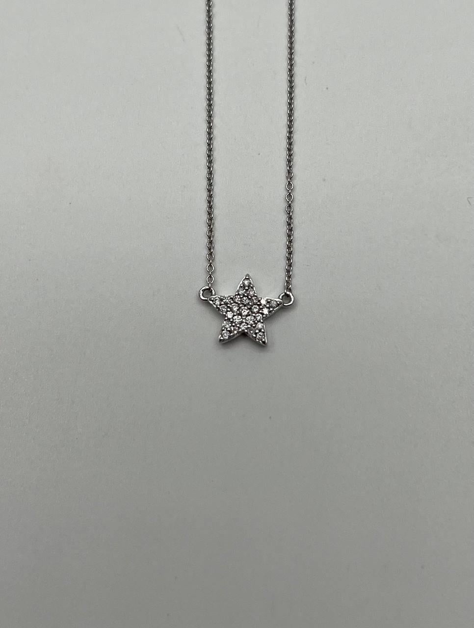 A charming diamond star pendant necklace. It features a star-shaped pendant adorned with white diamonds, totaling 0.15 carats. The diamonds are set in a sparkling pattern that enhances the star's brilliance. The necklace is crafted from 14k white