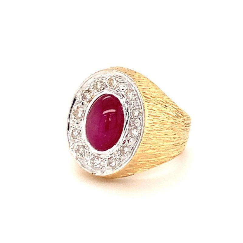 One star ruby and diamond 18K yellow gold ring featuring one bezel set, oval cabochon star ruby weighing approximately 5 ct. surrounded by 12 pave set, round brilliant cut diamonds weighing approximately 0.80 ct. With heavily textured, hand engraved