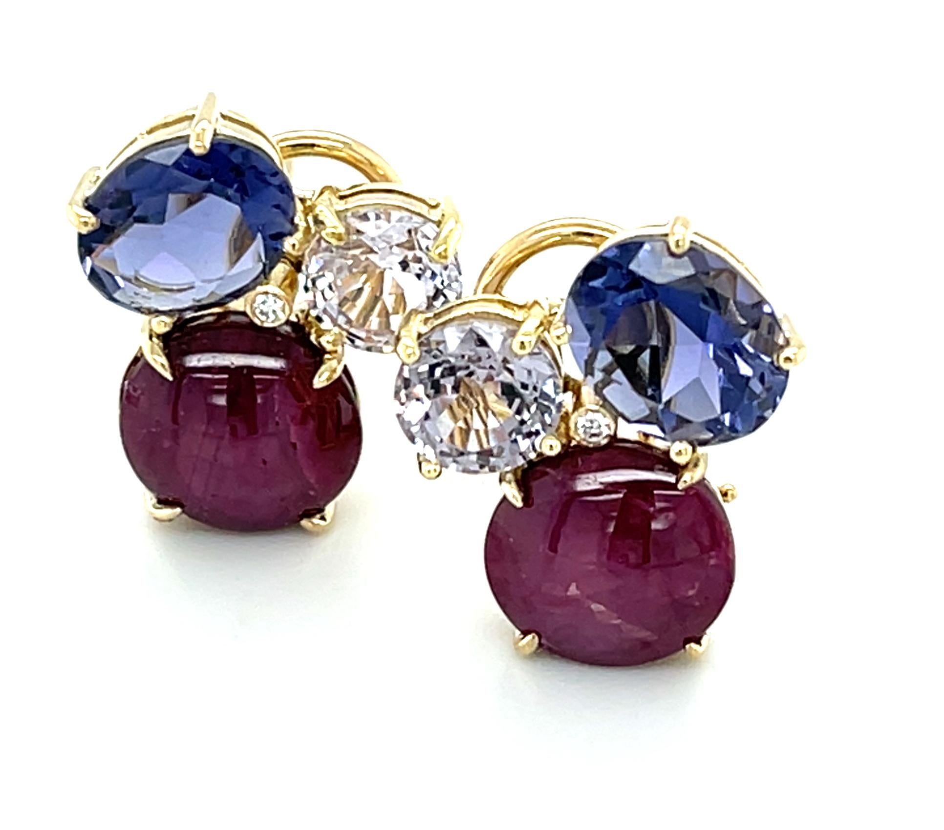 These stunning earrings feature a beautifully eye-catching arrangement of oval star rubies, iolites and lavender spinels! The large star rubies, weighing 11.60 carats combined, have rich, purple red color and clear, straight stars that exhibit