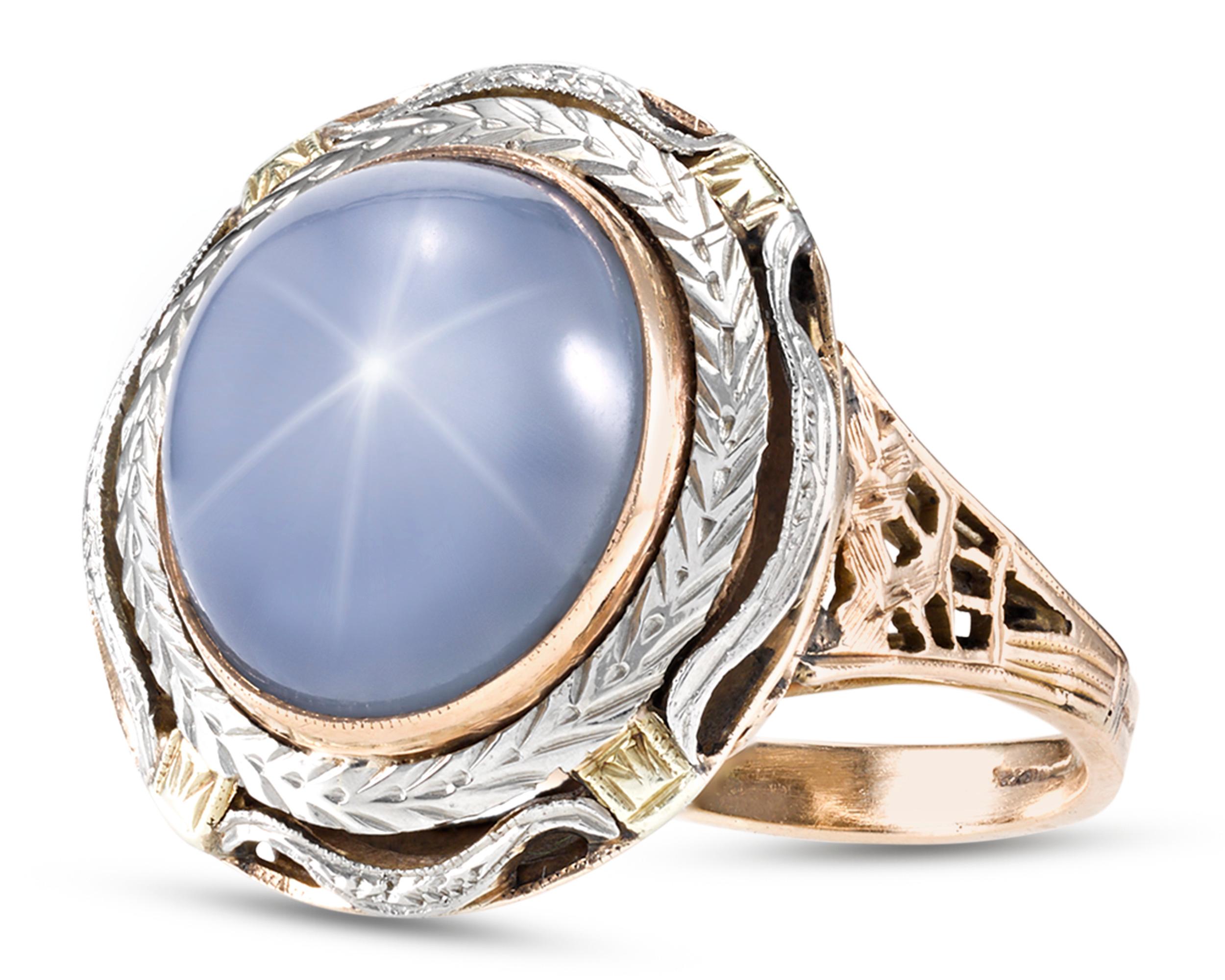 An incredible 12.39-carat star sapphire showcases a luminous cornflower blue hue in this striking ring. The fabulous cabochon jewel is set in wonderfully engraved platinum and 18K yellow gold setting featuring a laurel motif and pierced elements