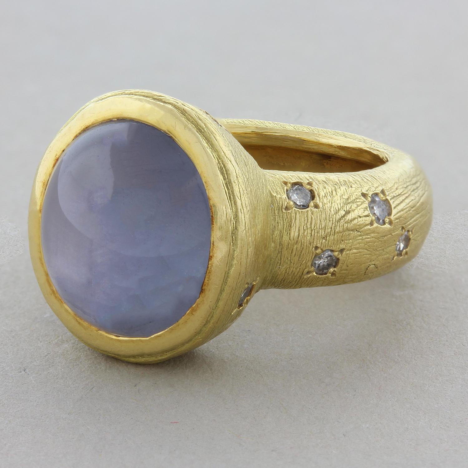 A delicately smooth 13.57 carat oval cabochon star sapphire is bezel set in this fun ring polka-dotted with 0.20 carats of diamonds. Set in 18K yellow gold with a textured finish.  

Ring Size: 4.75 (Sizable)
