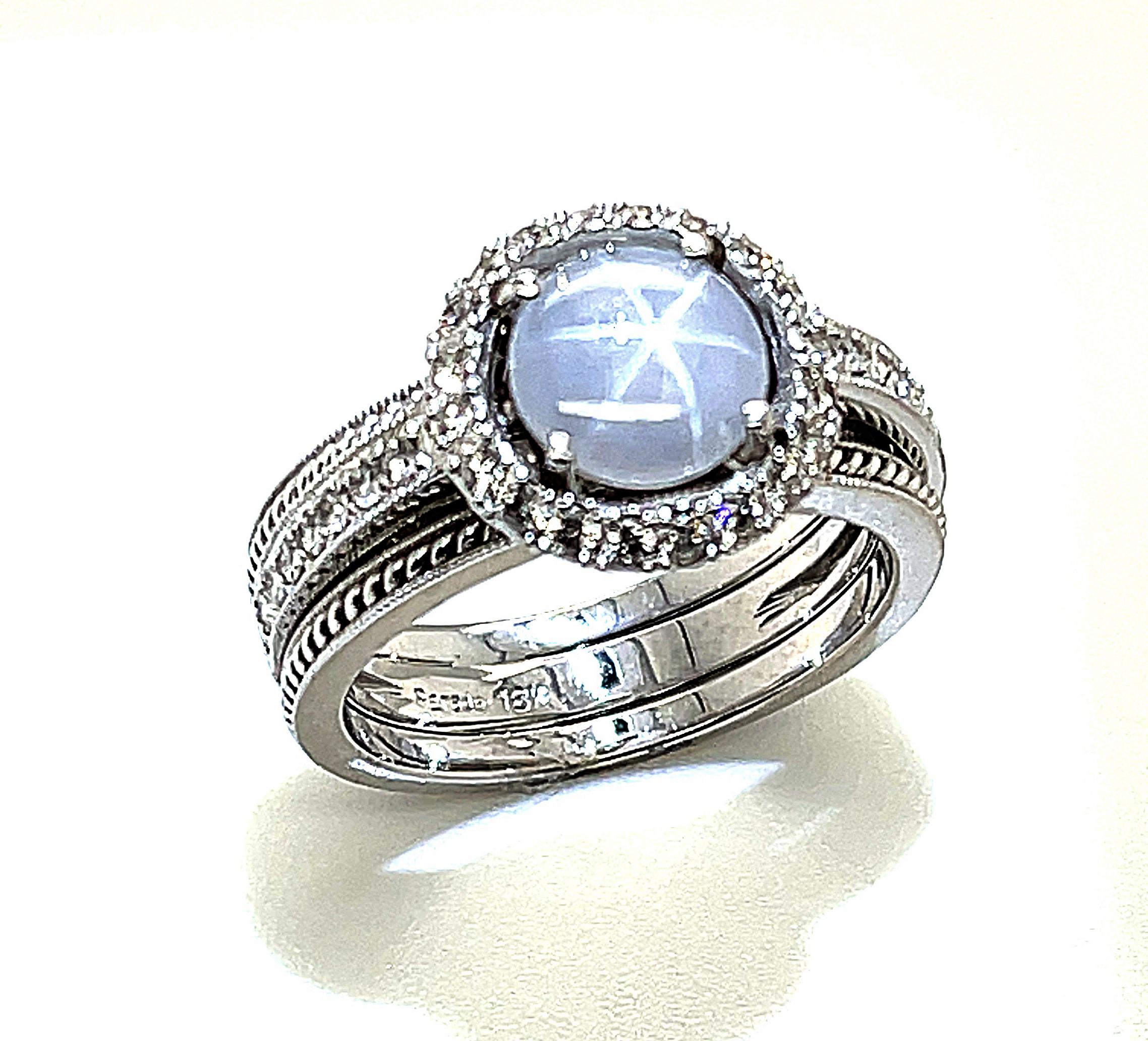 This ring is a beautiful statement of both quiet elegance and originality. Featuring a violetish-grey star sapphire with a bright 6-rayed star when viewed in focused light, this ring combines a variety of textures to create an eye-catching ring that