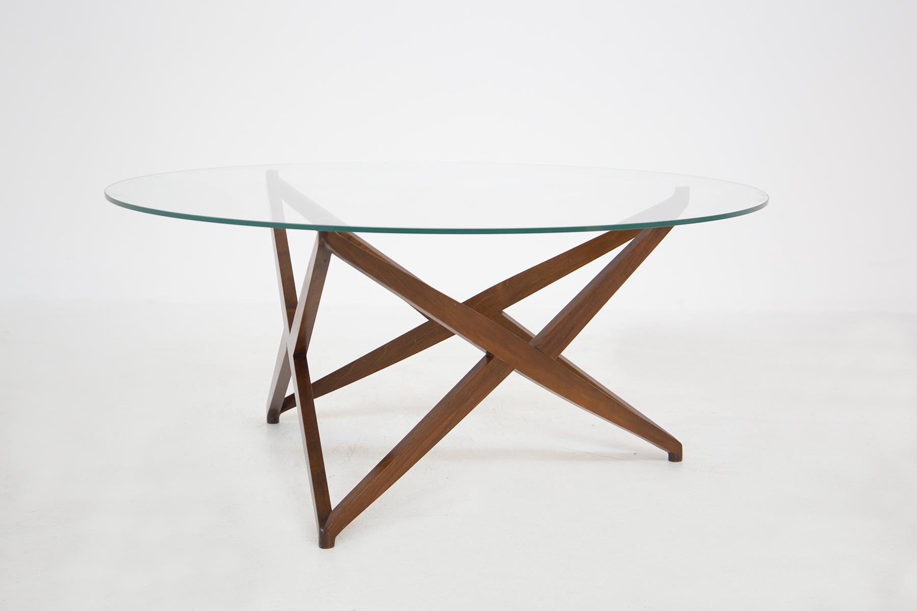 Splendid coffee table in wood and glass designed by Angelo Ostuni in the 60s, of fine Italian manufacture.
The coffee table is particular because its legs create a wonderful star, visible from the glass.
The table top is round and is in a splendid