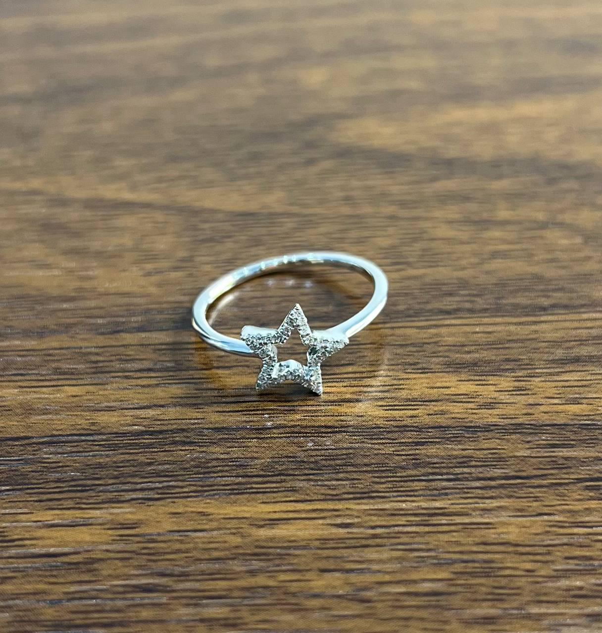 A striking star ring with 14K White Gold and 0.15 CTW G/VS Quality White Diamonds. This elegant ring features a delicate open star design, crafted in a sleek silver tone. The star is adorned with a subtle texture, adding a touch of sparkle and