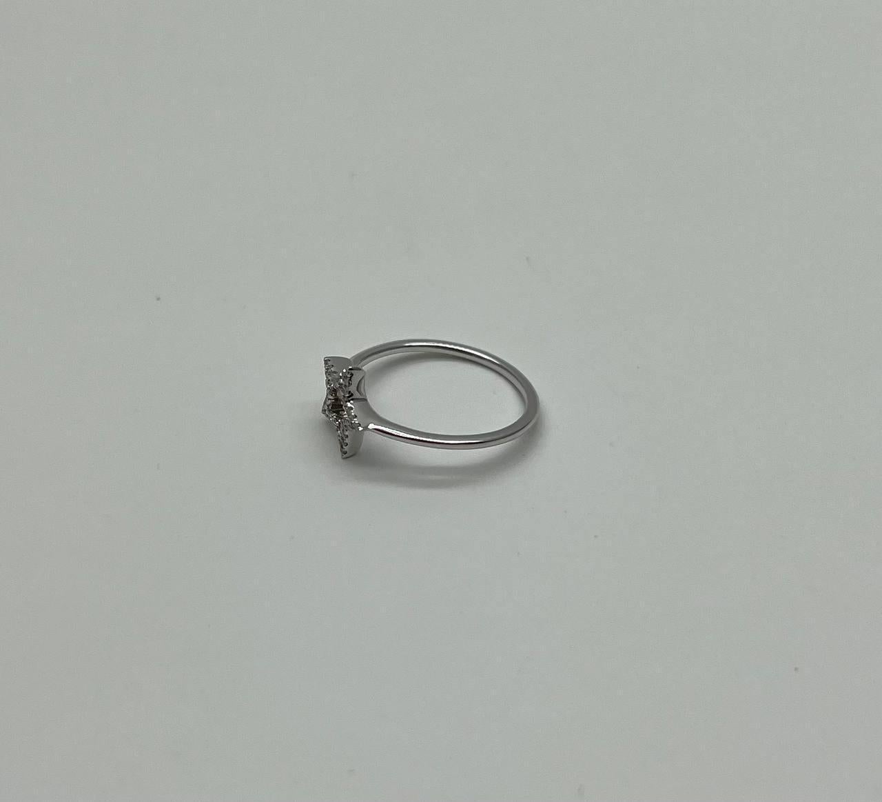 Eine minimalistische Erkundung von Form und himmlischem Schimmer. Dieser auffällige Ring hat ein zartes, sternförmiges Design, das mit funkelnden Steinen besetzt ist. Das offene Sternmotiv ist auf einem glatten, polierten Band eingefasst, das einen