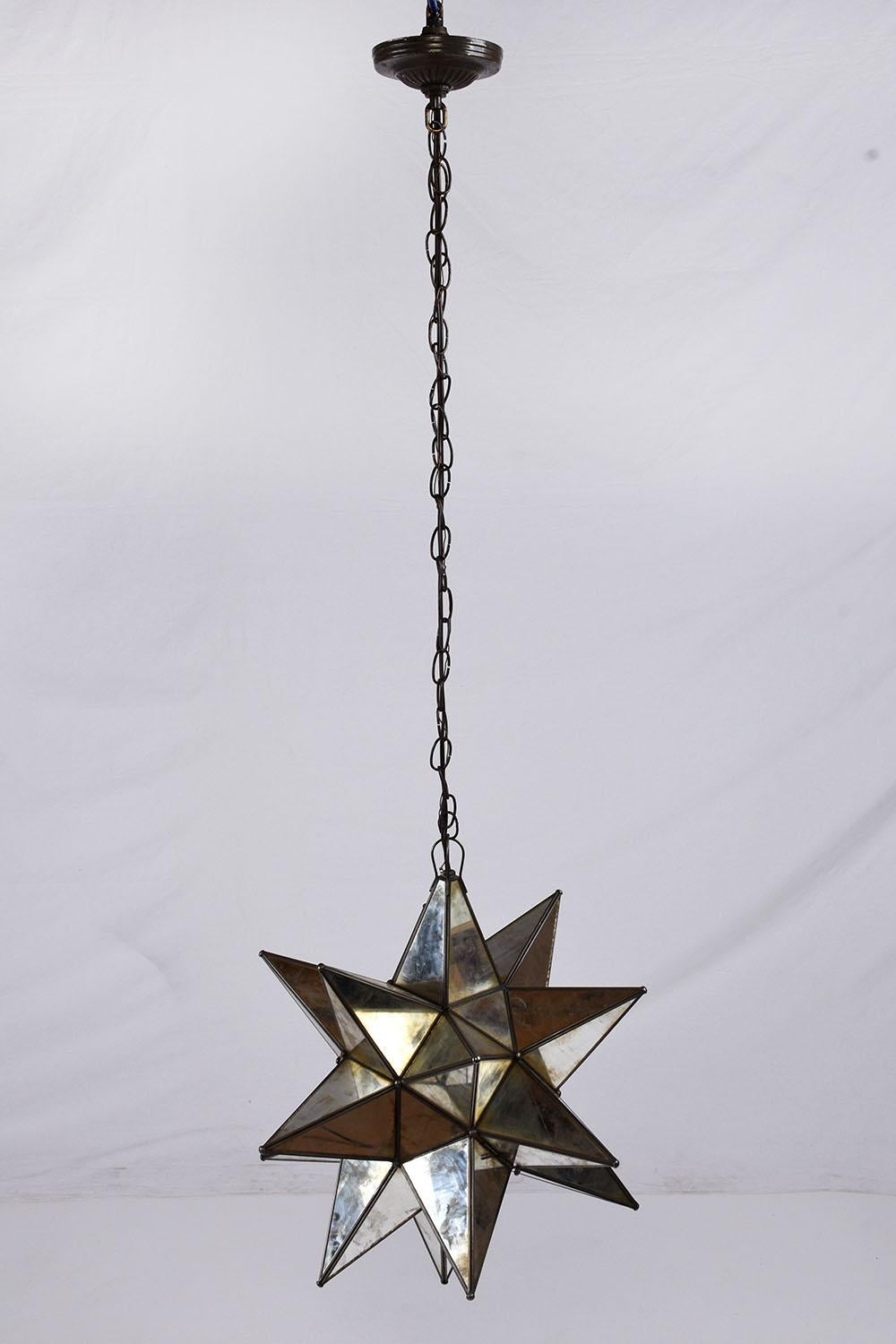 This 1980s mid-century modern-style chandelier has an eye-catching starburst design and has been newly restored by our team of expert craftsmen. The star points are adorned with distressed mirrors separated by metal pieces with a section that lifts