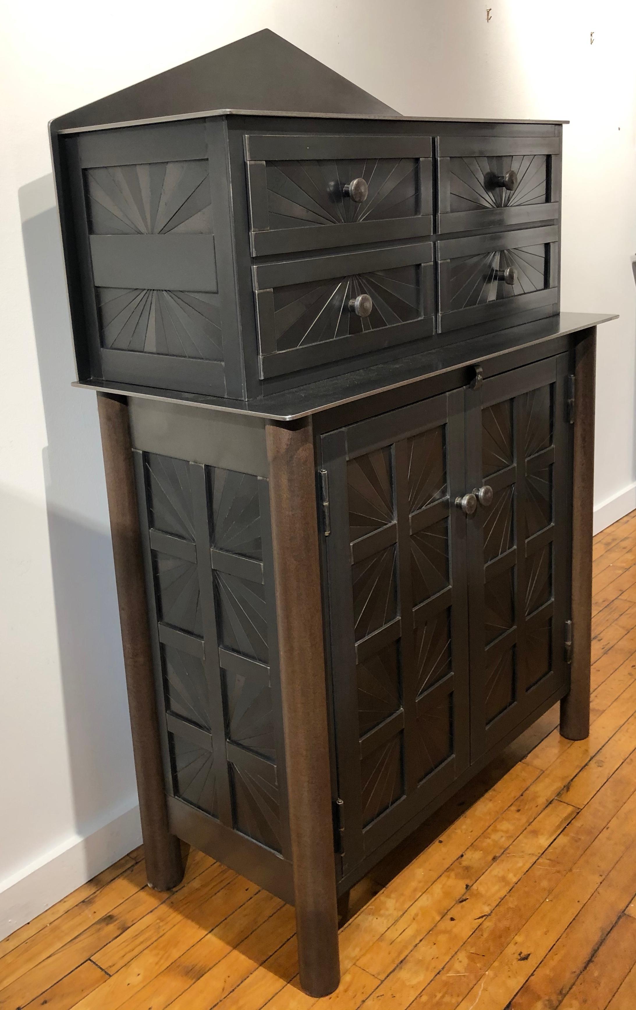 This is a totally functional cupboard is topped with a chest of drawers. It is created from hot rolled steel and found steel. The legs are made from salvaged pipe. The starburst panels are inspired by the Quilts of Gee's Bend Alabama. The blue-gray