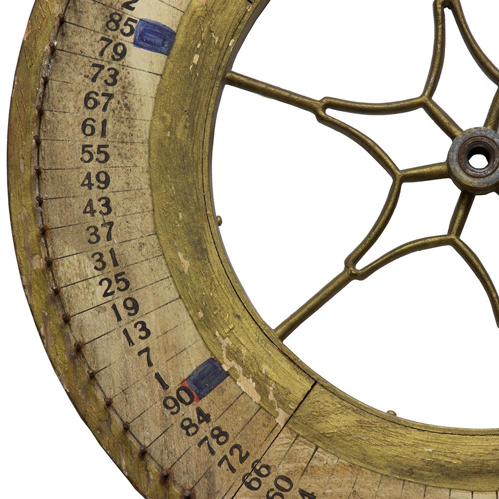 This antique game wheel has hand painted numbering with a central brace shaped like a starburst.
