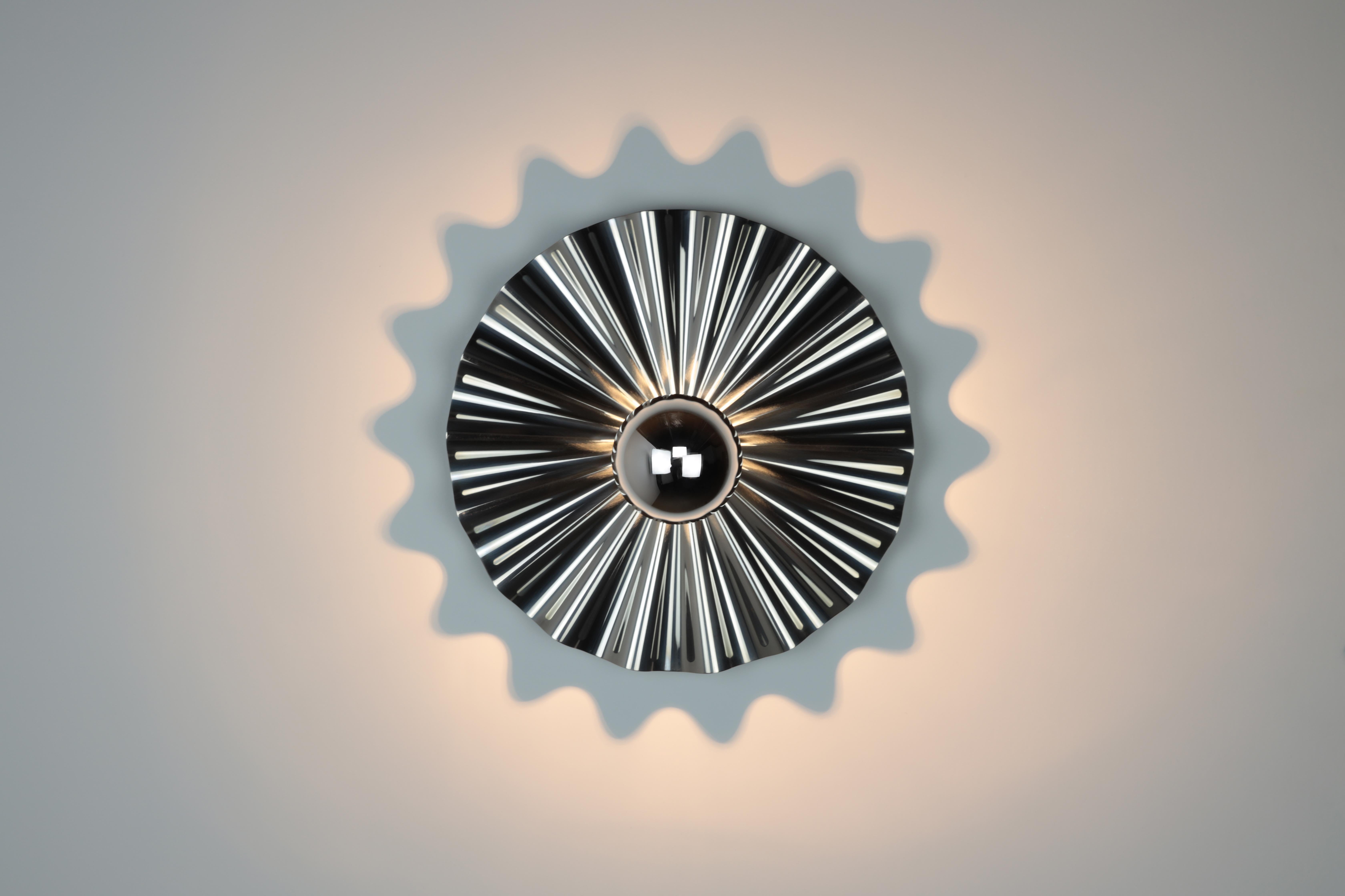 An explosion of light reflects and spills onto the wall from a corrugated metal surface. The starburst sconce is made of polished stainless steel with a medium socket bulb. A half dipped chrome bulb is included.
Made in Los Angeles.