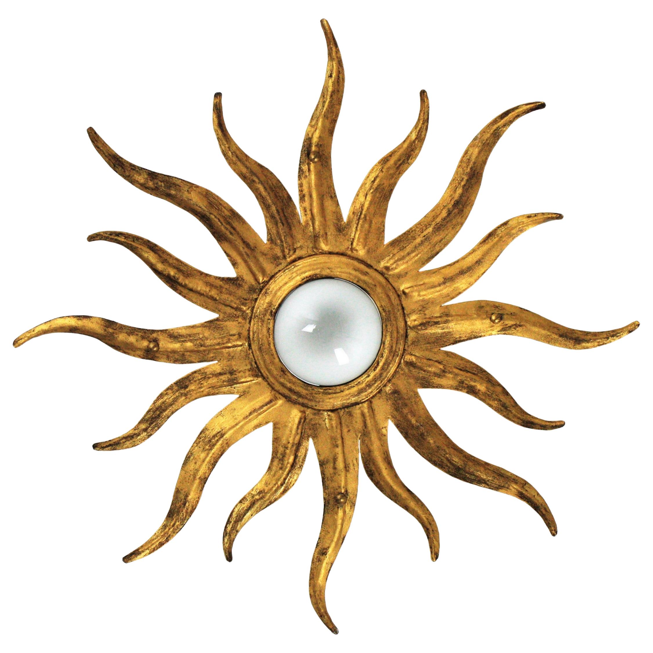 Sunburst starburst flushmount ceiling light fixture in gilt metal, Spain, 1950s
This beautiful hand-hammered gilt iron starburst flush mount with exposed bulb was manufactured at the Mid-Century Modern period with Brutalist and Hollywood Regency