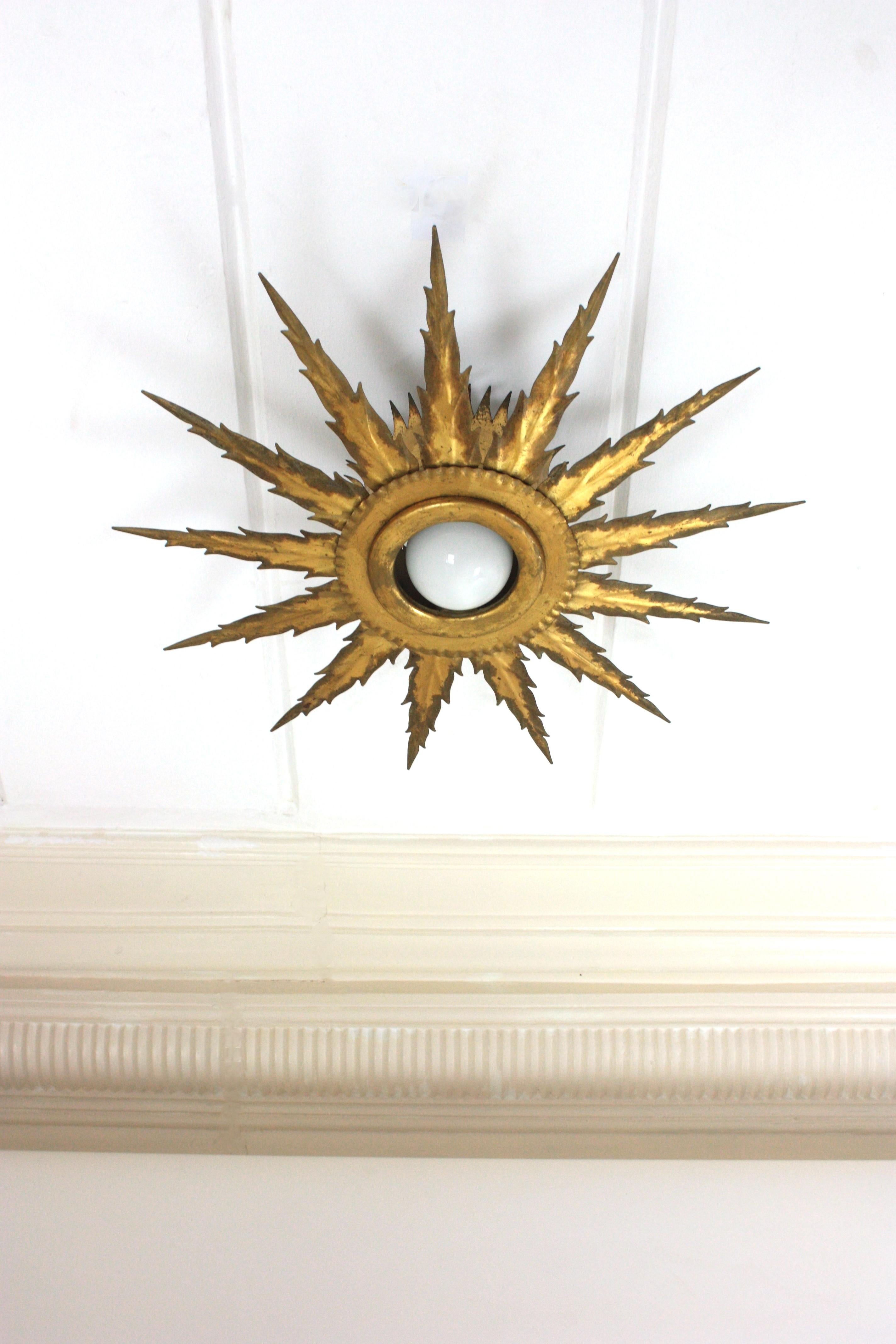Rare luminaire encastré en fer doré en forme de soleil ou d'étoile. Espagne, années 1940-1950.
Ce miroir brutaliste présente deux couches de rayons de tailles différentes avec des bords pointus et dentelés. Il présente une superbe patine vieillie à