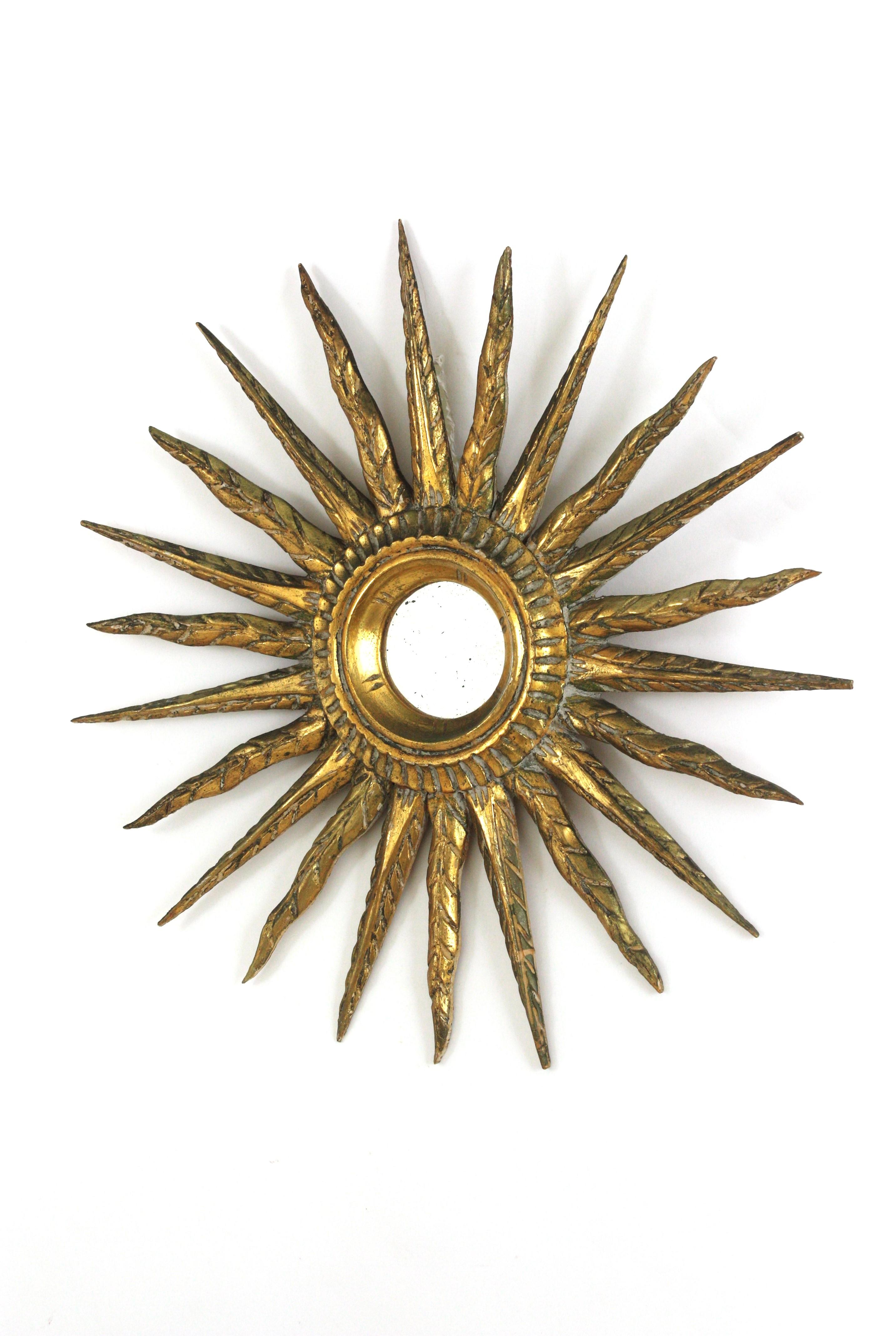 Hollywood Regency Starburst Sunburst Mirror, Carved Wood, Gold Leaf, Spain 1940s.
Hand carved sunburst mirror with gold leaf gilding.
A very beautiful sunburst mirror finely carved with 24 k gold leaf finish and greenish accents. 
Very unusual size