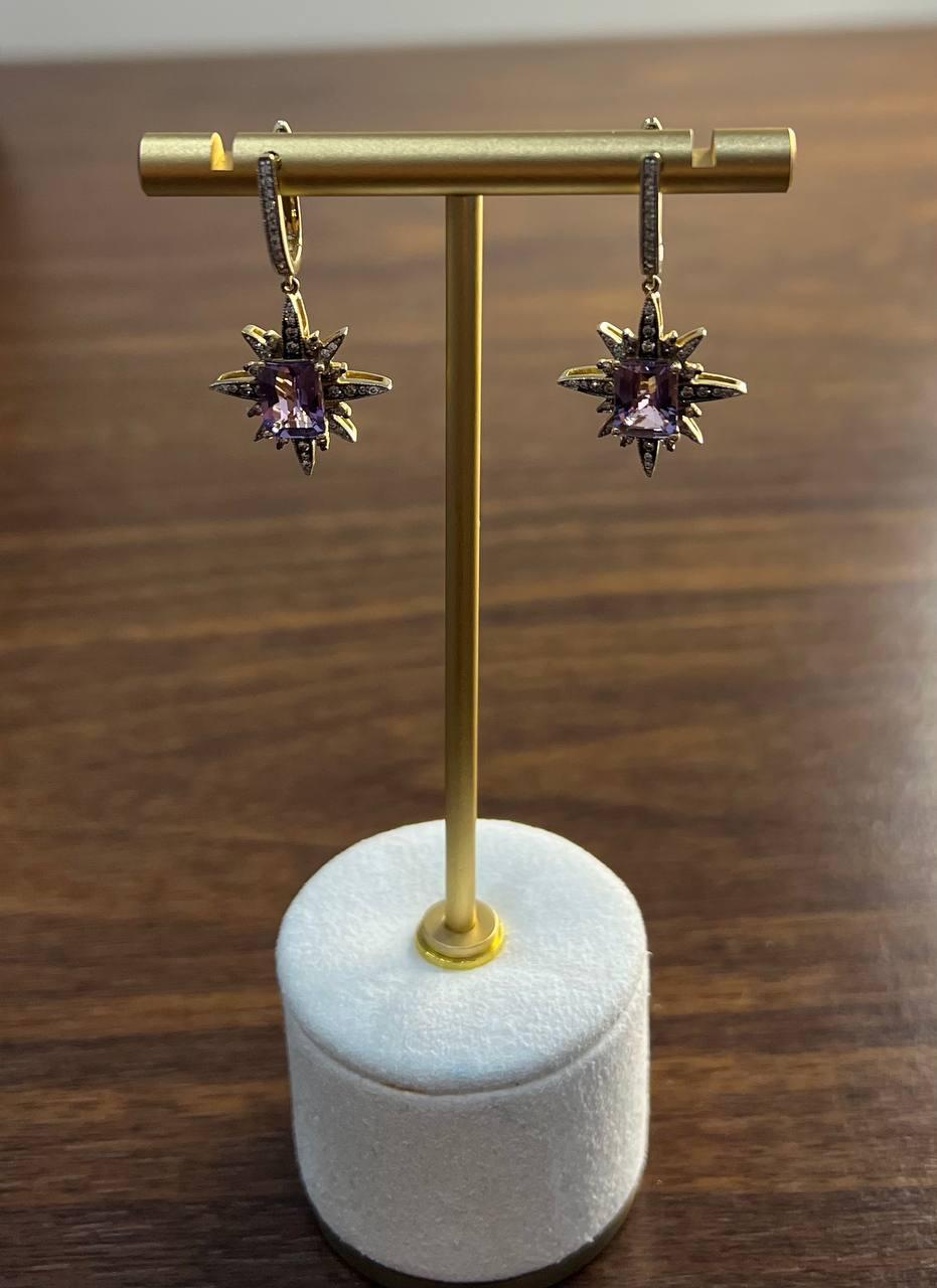 Discover the elegance of these exquisite dangle earrings.

Featuring a captivating starburst design, each earring showcases a central amethyst gemstone, surrounded by intricate spikes adorned with shimmering diamond accents.

Crafted with precision,