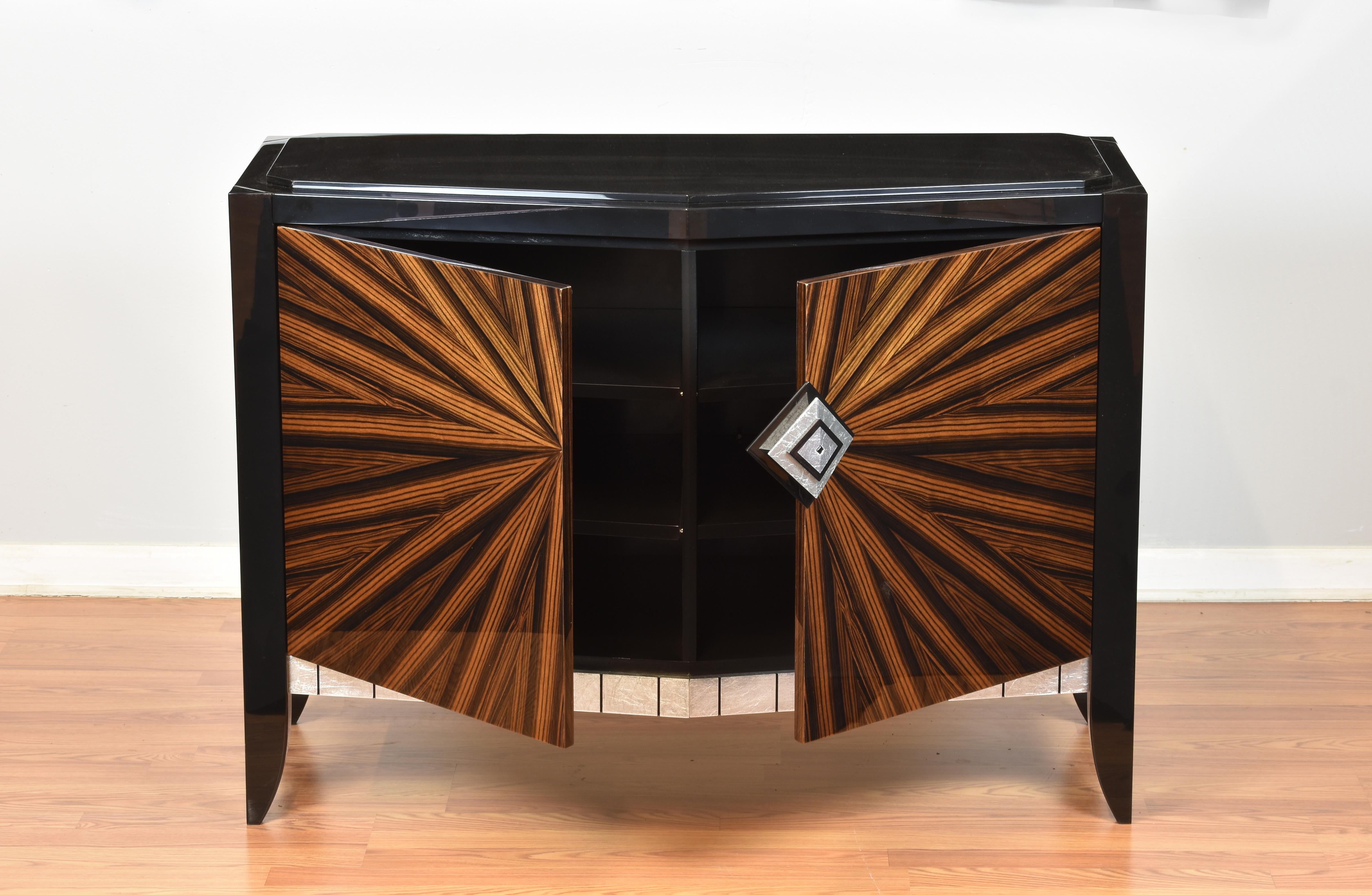 Chevron accent cabinet Chicago version is part of the Chevron series. It has a black granite top which complement the starbust ebony macassar door fronts There are jet black maple legs and leg tops which highlight the silver leaf bottom trim with