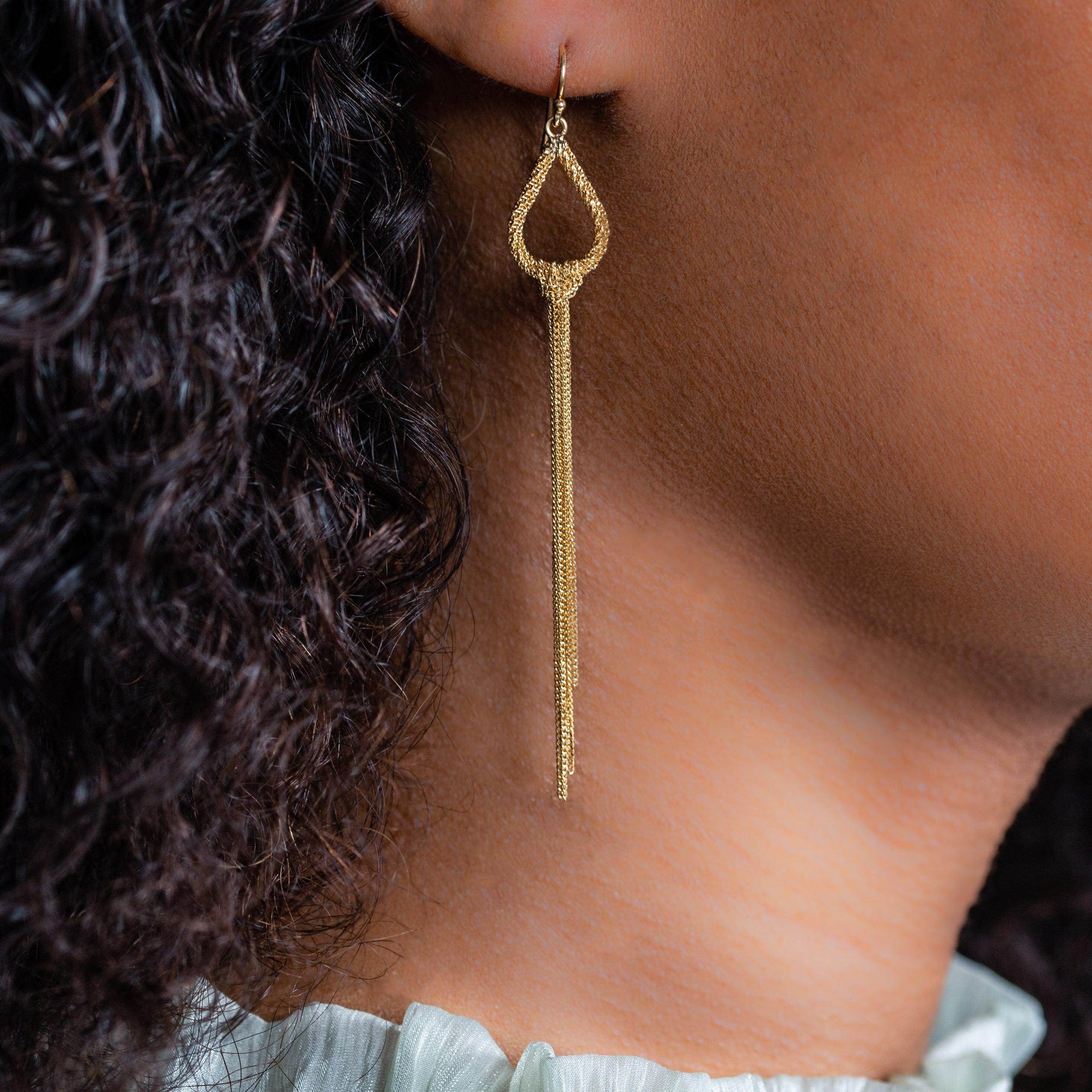 These tantalizing tassel earrings begin with a light and lovely open pear shape of hand-woven 18K yellow gold. A bundle of gold chain is then looped around the curved base of each pear, cascading downward in a bright banner of precious metal that