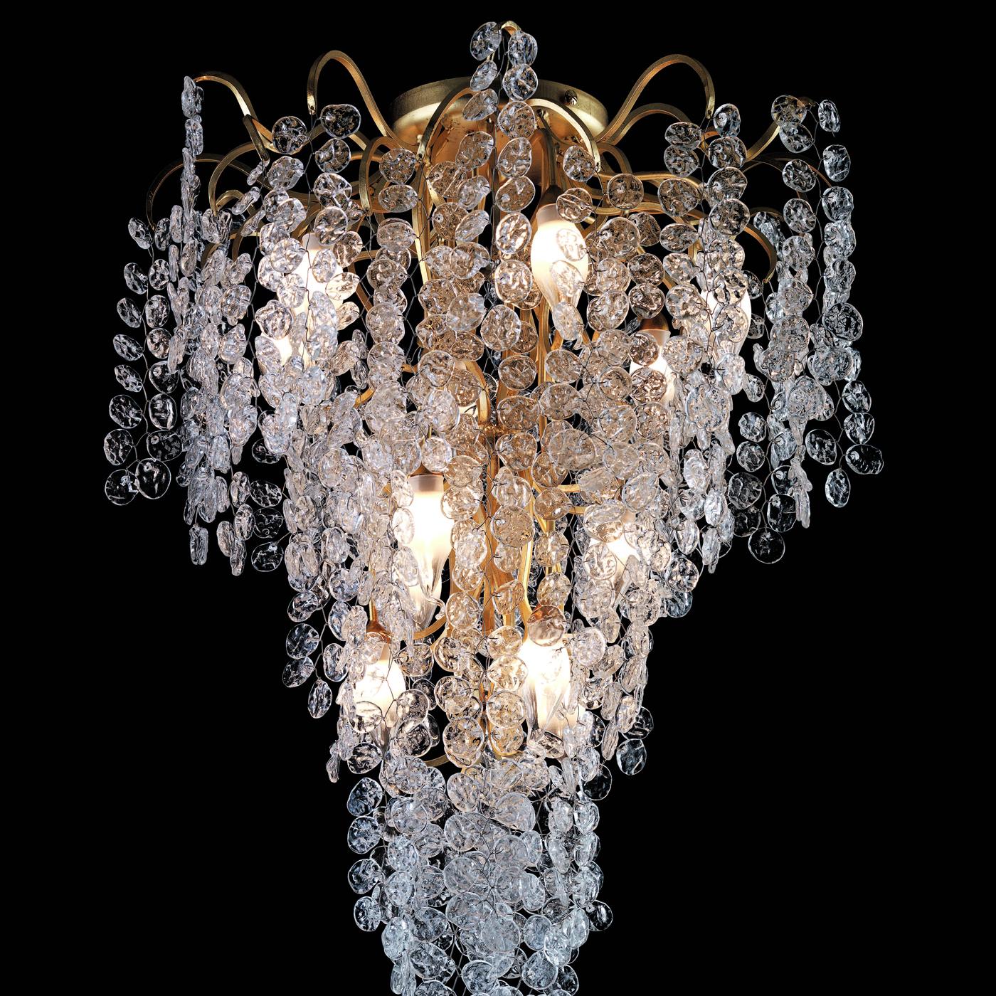 Showcasing a curvy metal frame richly covered in luminous gold leaf, the stately design characterizing this chandelier derives from the long cascade of transparent glass petals pending from its arms to which are minutely hand fixed. Twelve ES bulbs
