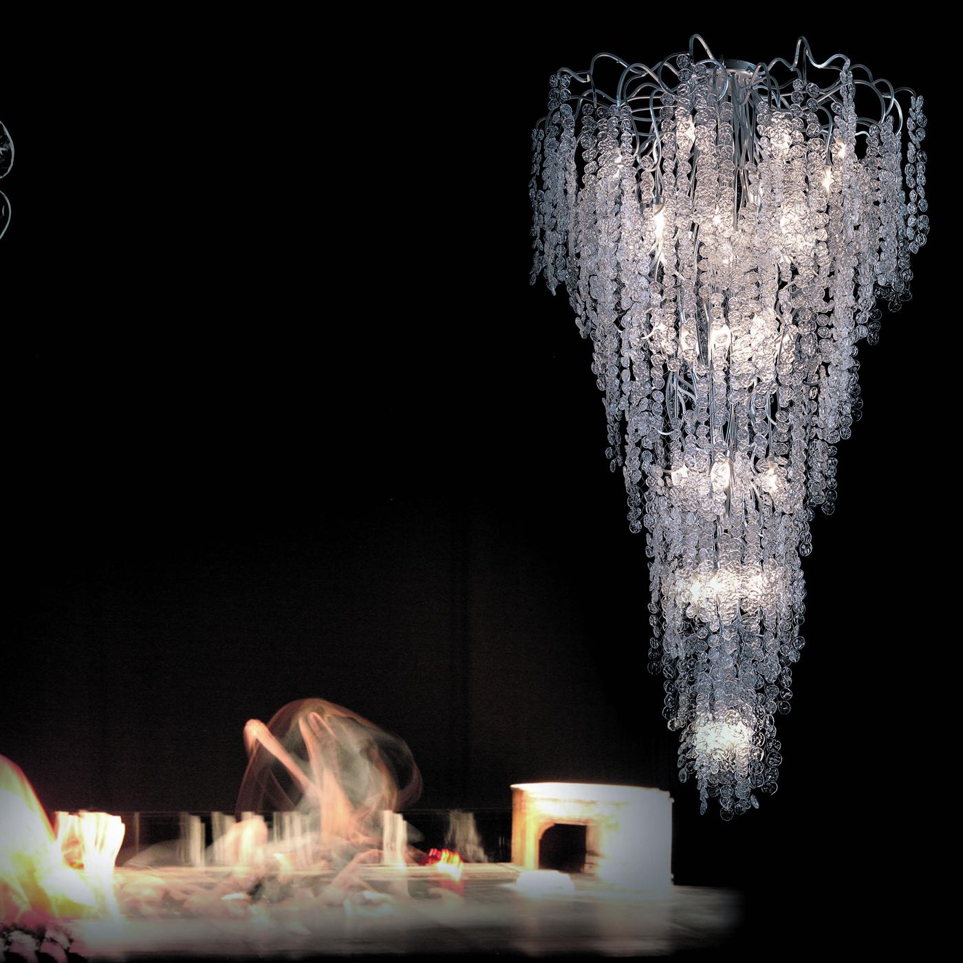 An object of spectacular visual impact thanks to its sumptuous design, this chandelier boasts a Silhouette whose Cascade of graceful petals in transparent glass is minutely hand-fixed. The 35 ES bulbs (G9 33W each) are distributed on various tiers