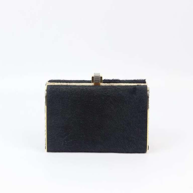 Stark calf hair and leather box clutch. Black and gold. Push lock fastening at top. Comes with dustbag. Height: 3.1 in. Width: 2.1 in. Depth: 2.5 in. Very good condition - No sign of wear; see pictures.